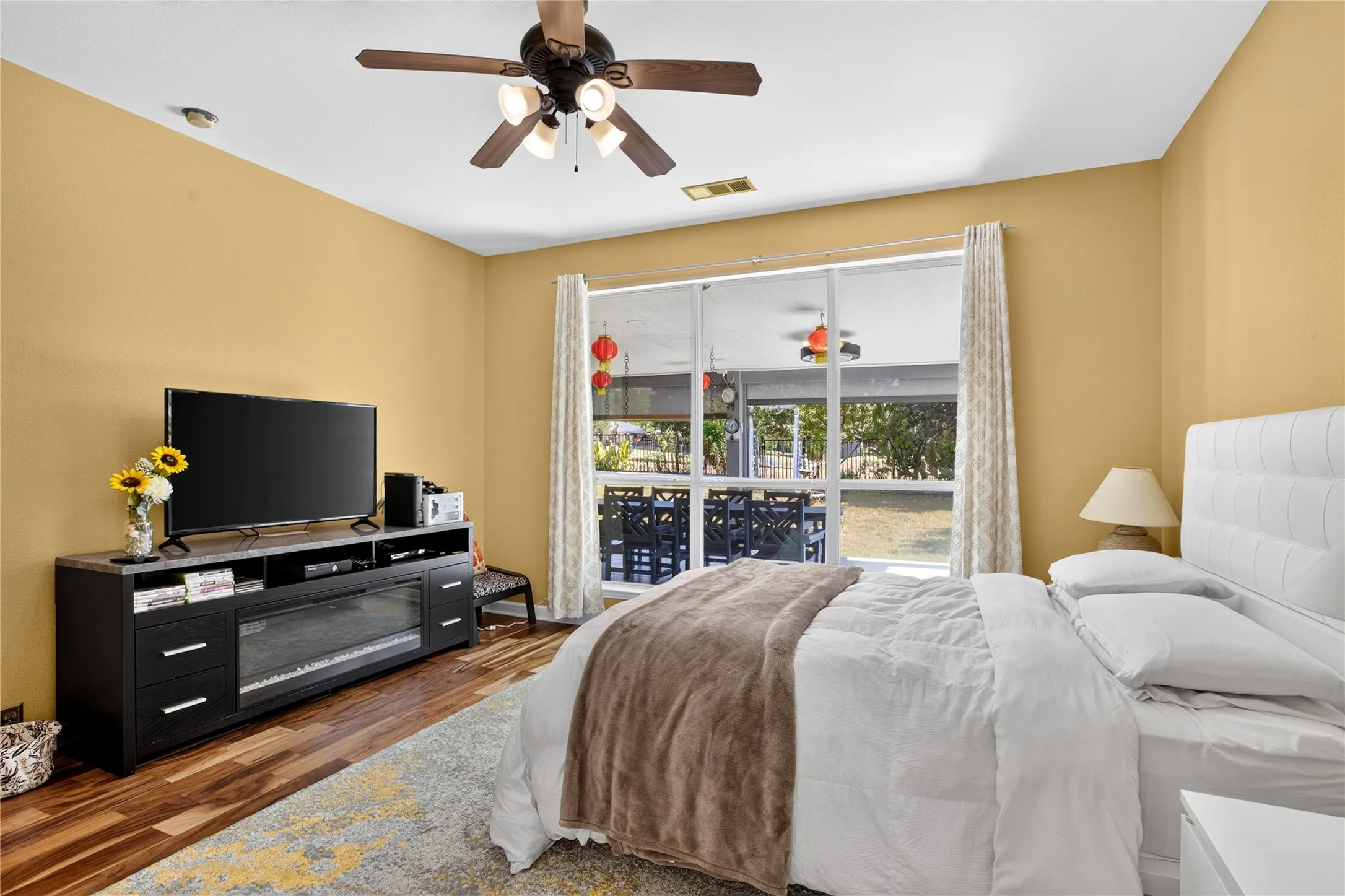 Wood-finish flooring, ceiling fan with integrated lighting, recessed lighting, and sliding glass doors to a screened patio