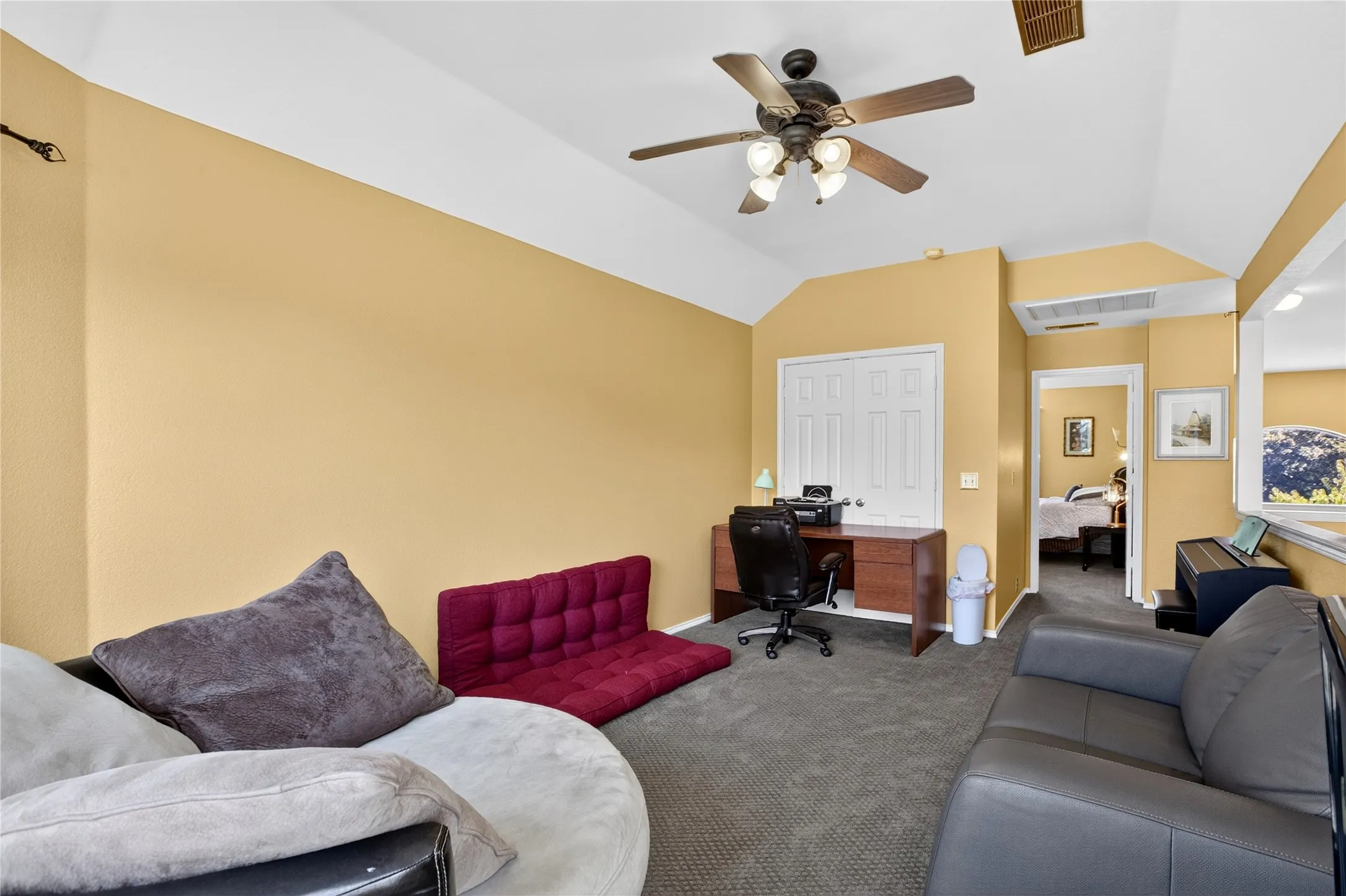 Vaulted ceiling with a ceiling fan, carpeted flooring, and a built-in desk area