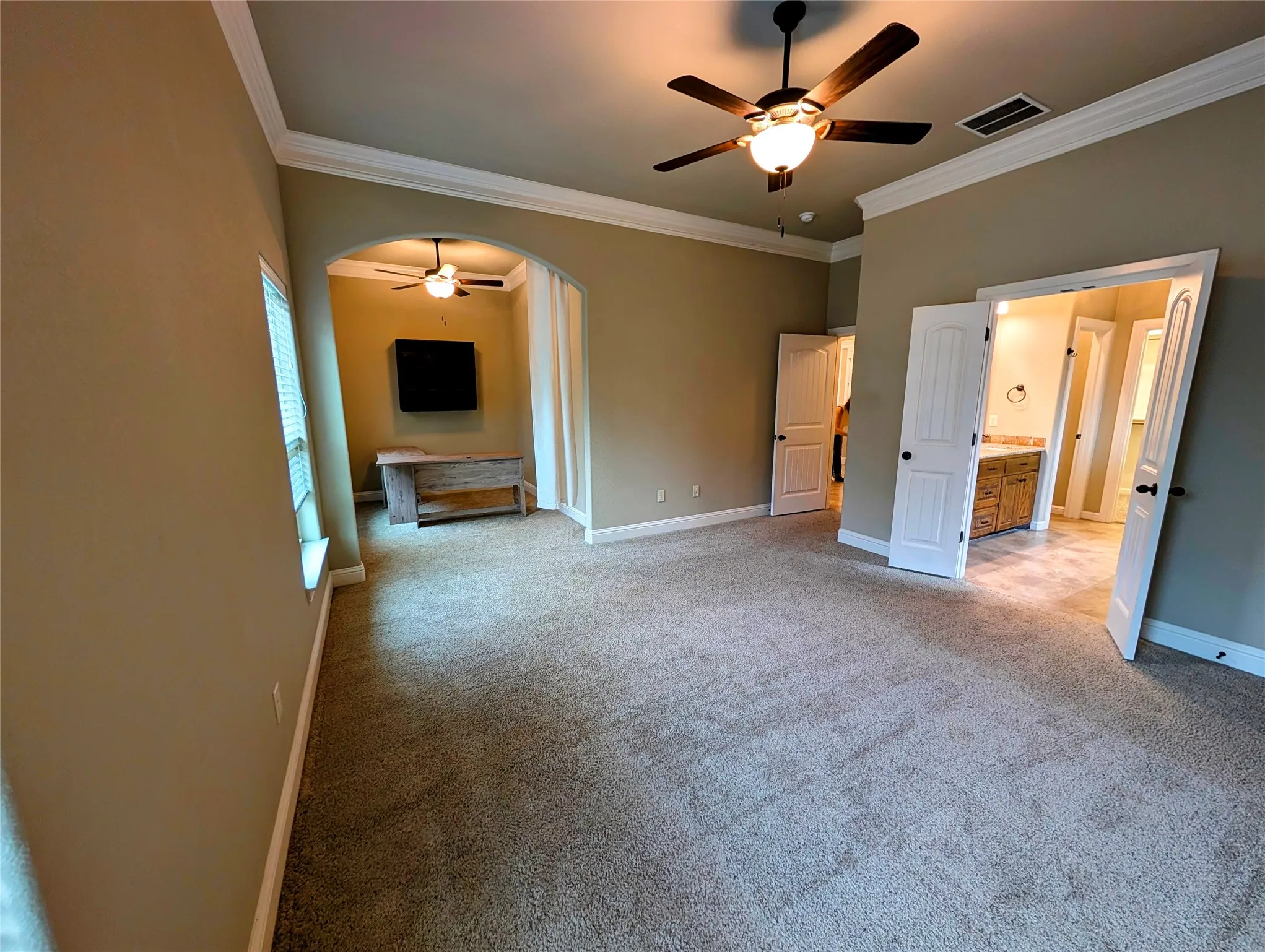 Tray ceiling with crown molding, ceiling fan, and carpet flooring