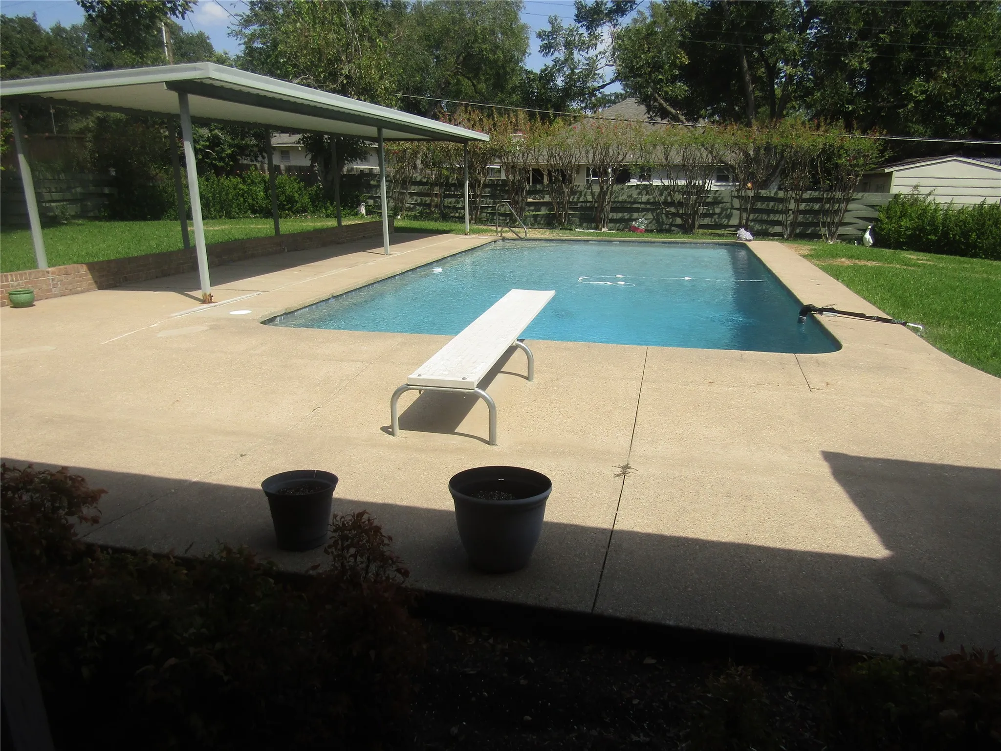 Rectangular swimming pool with a diving board, surrounded by concrete decking