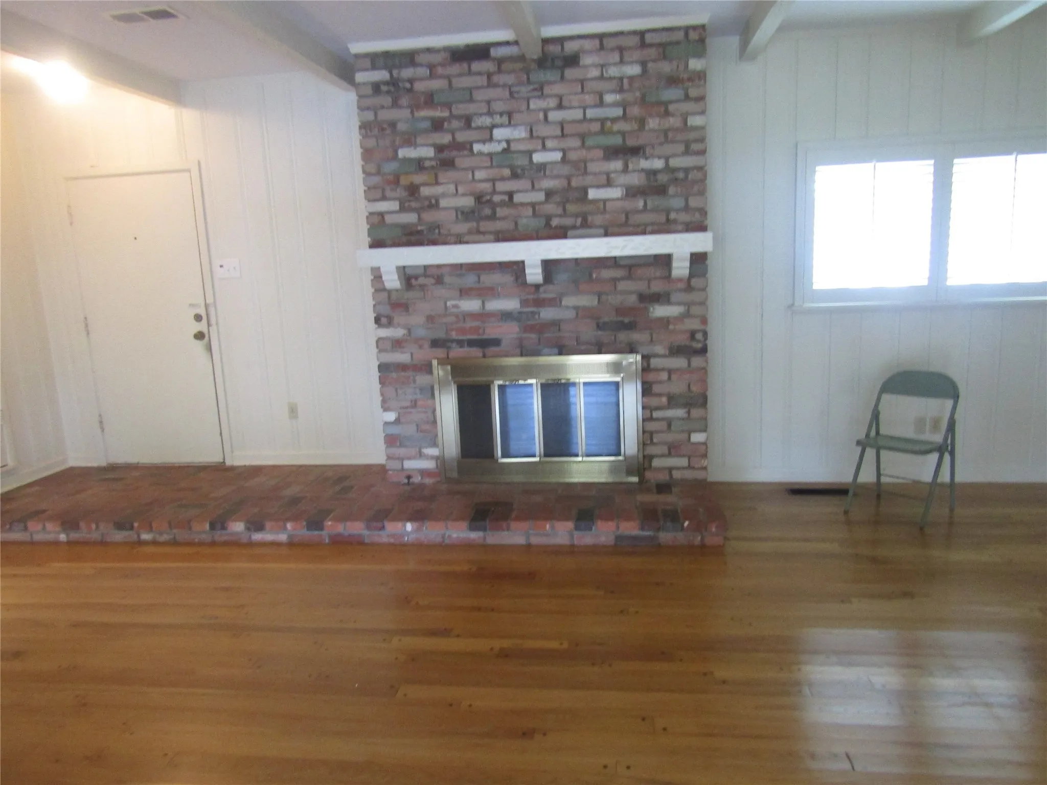 Brick fireplace with a brass firebox, a brick hearth, and a white mantel