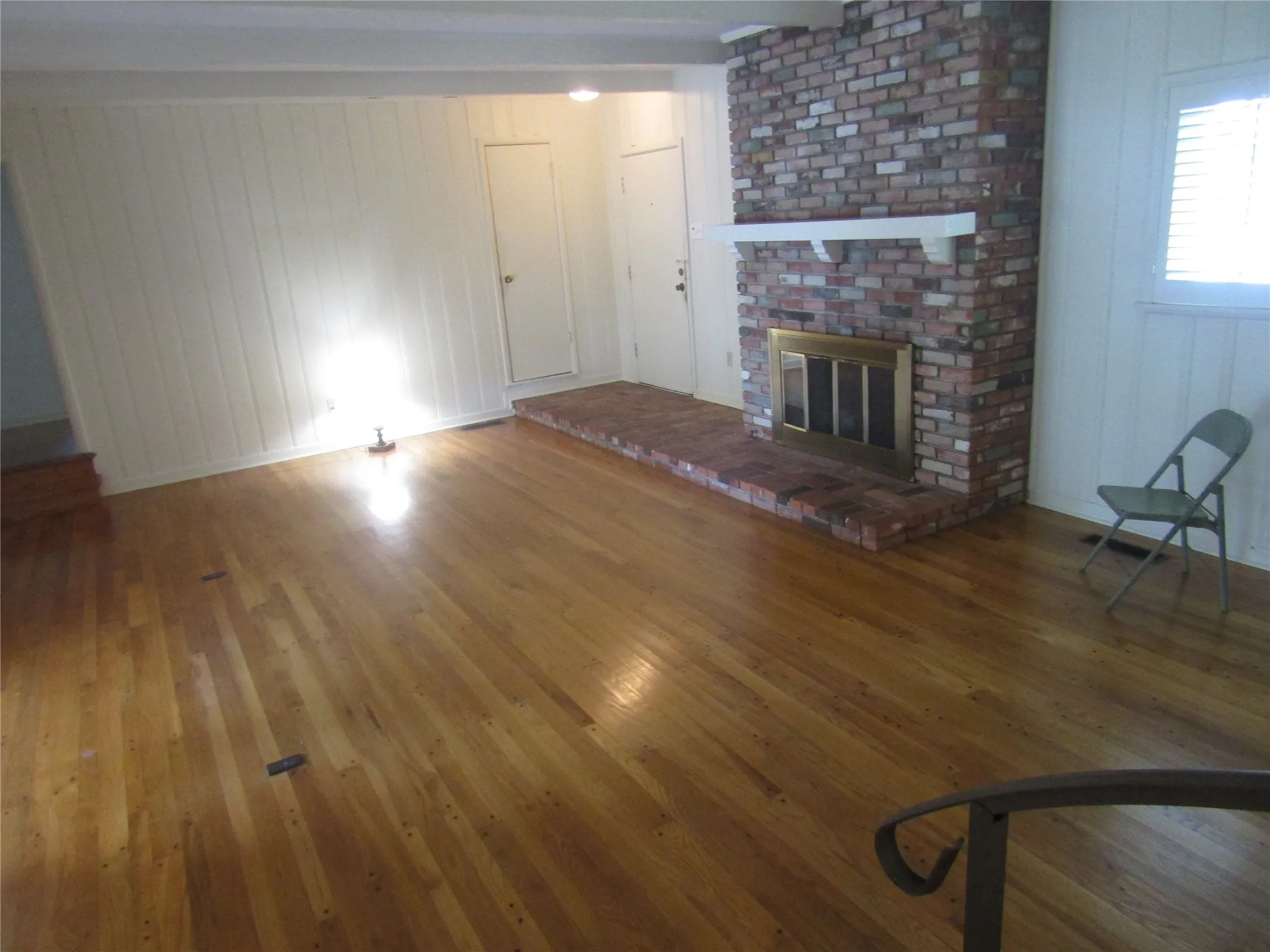 Brick fireplace with a brass firebox, white mantel, and brick hearth