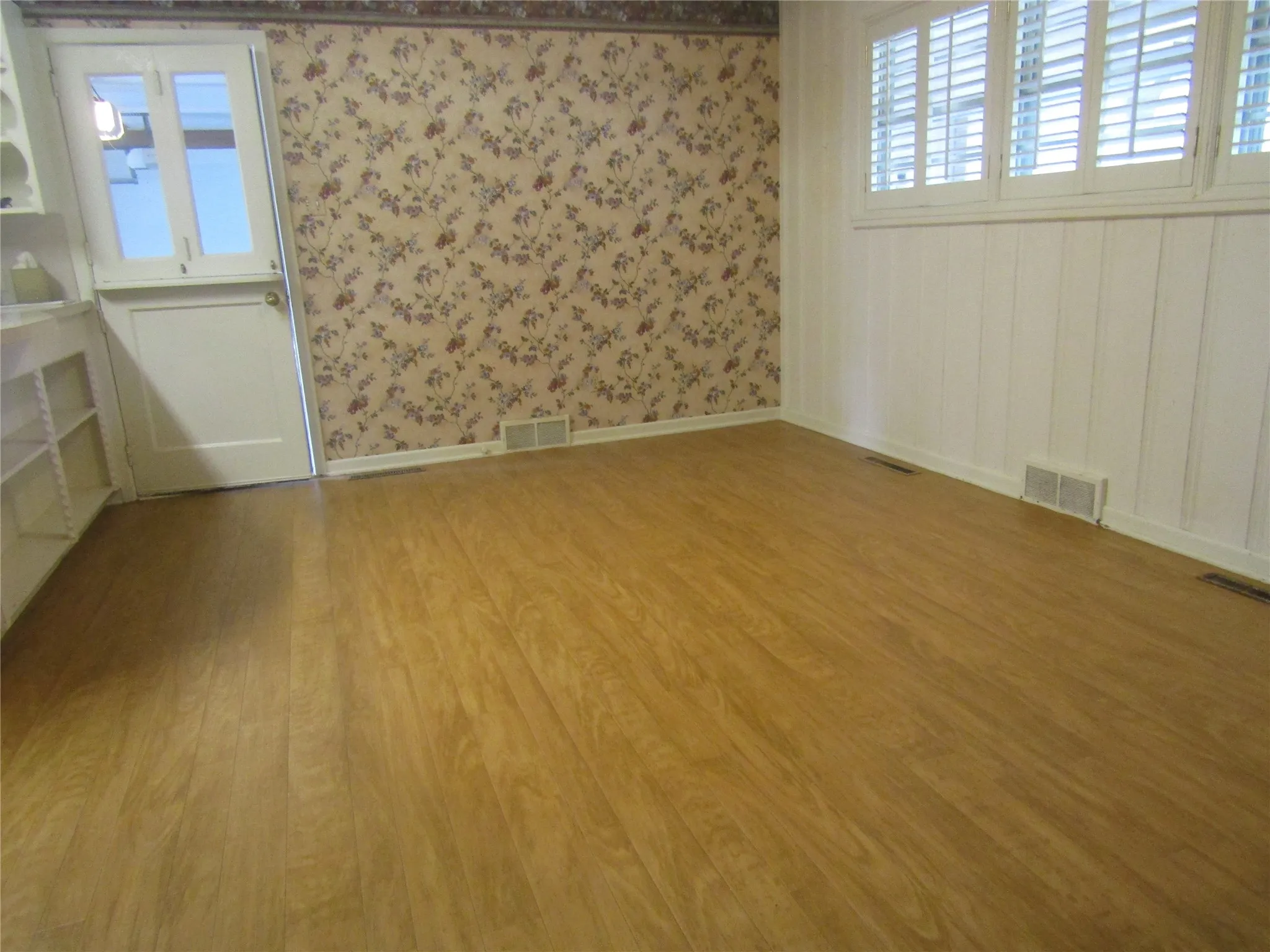 Wood-finish flooring with white baseboards, a white paneled door, and built-in shelving