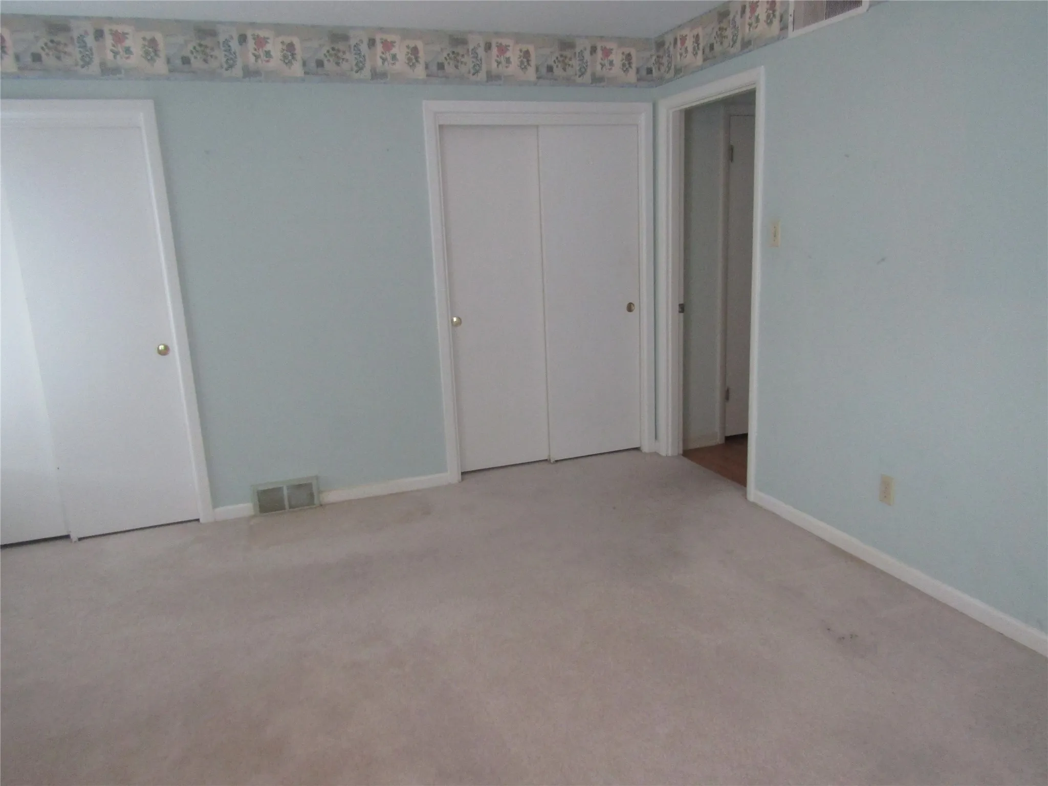 Wall-to-wall carpeting with multiple white doors, including a double sliding closet door