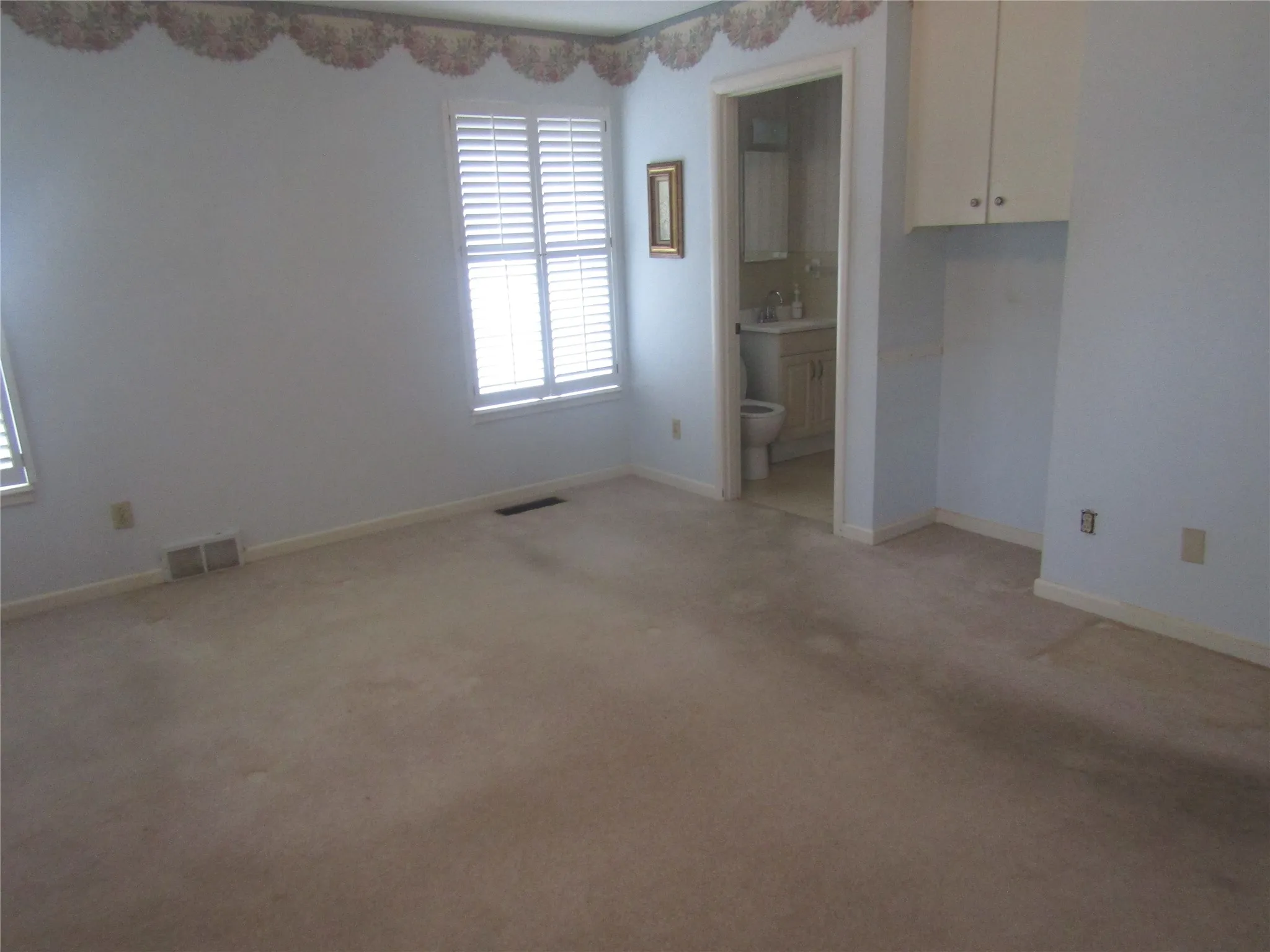 Interior room with neutral carpet, white walls, and built-in upper cabinetry