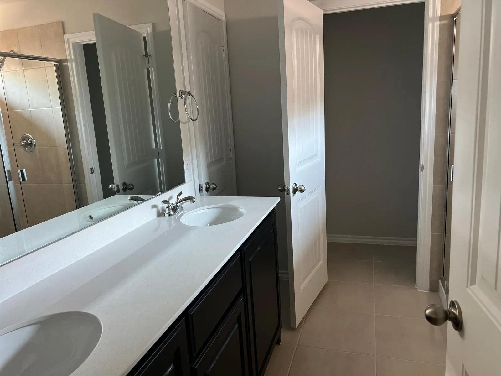 Full bathroom featuring light tile patterned flooring, a shower stall, and double vanity