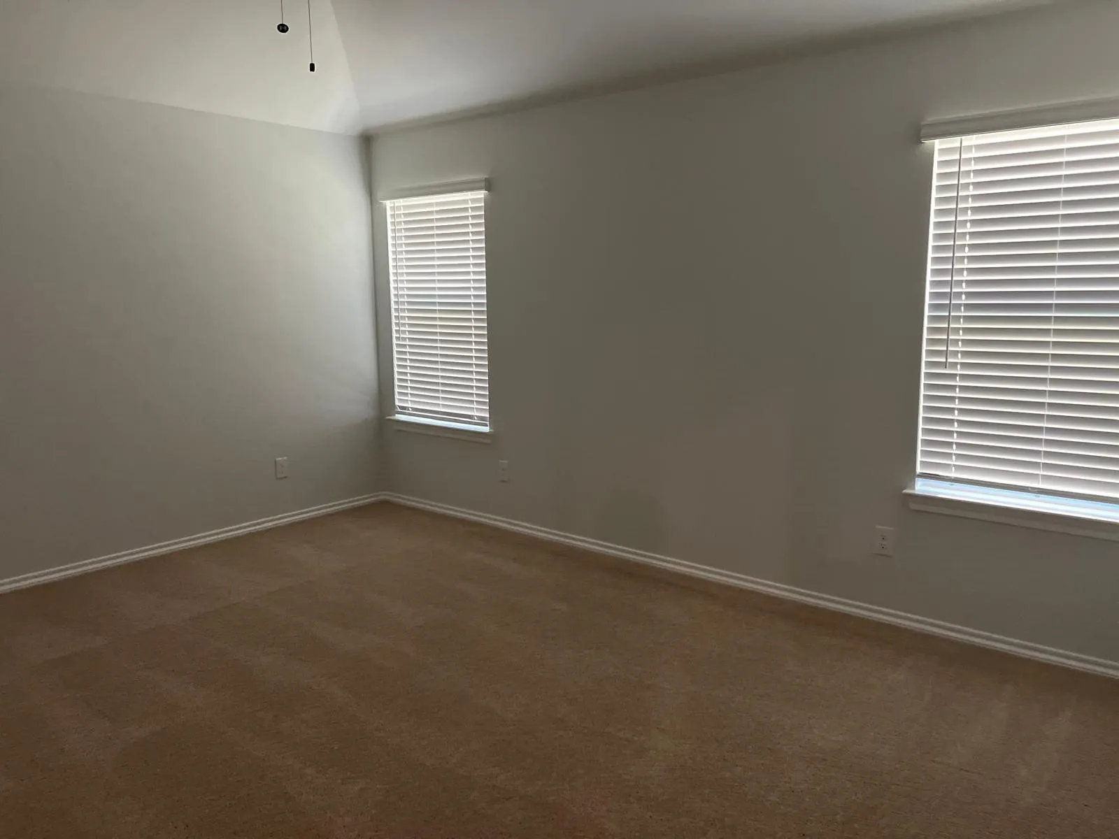 Spare room featuring dark colored carpet, a ceiling fan, and vaulted ceiling
