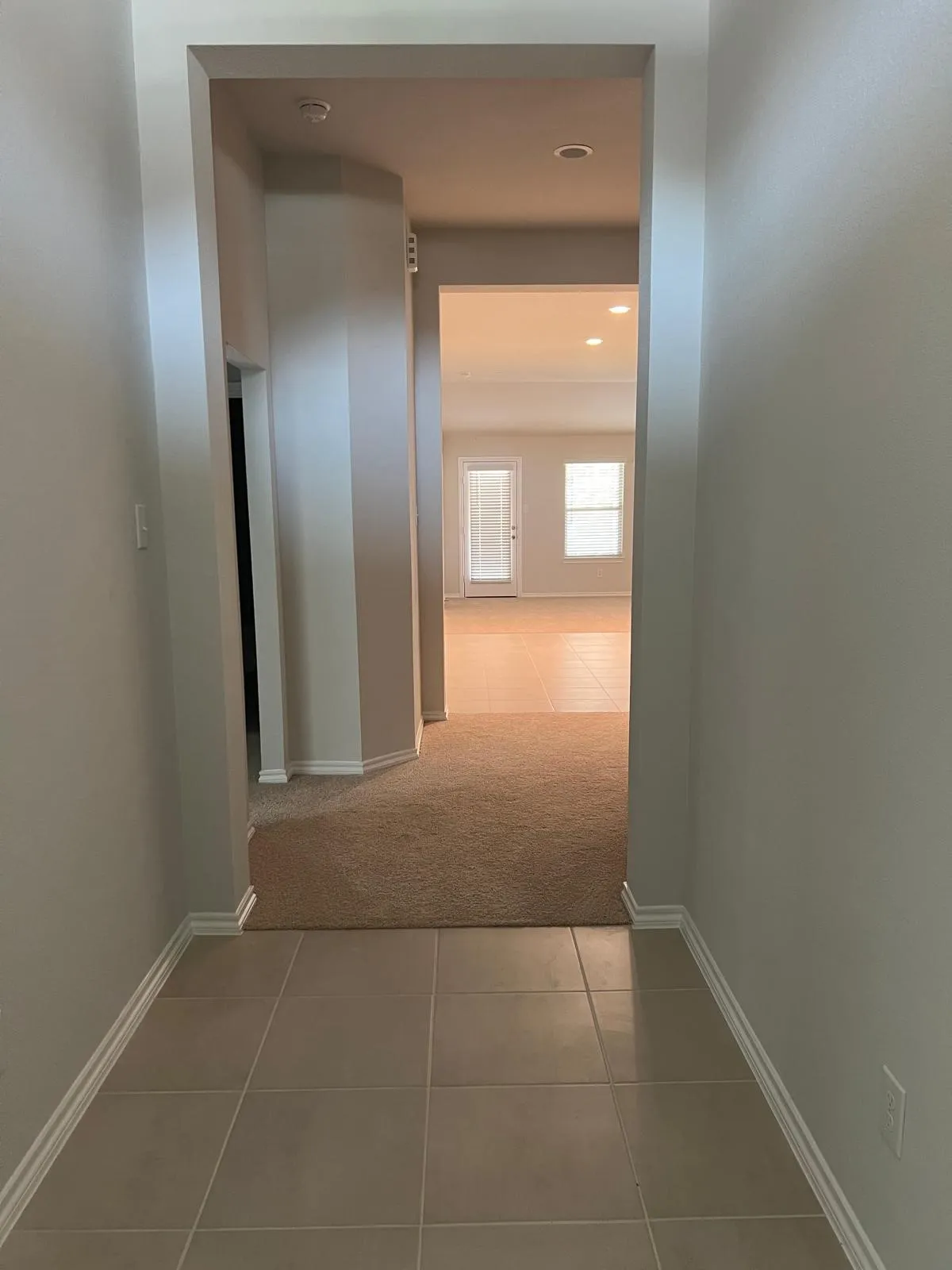 Hallway with light tile patterned floors, light carpet, and recessed lighting