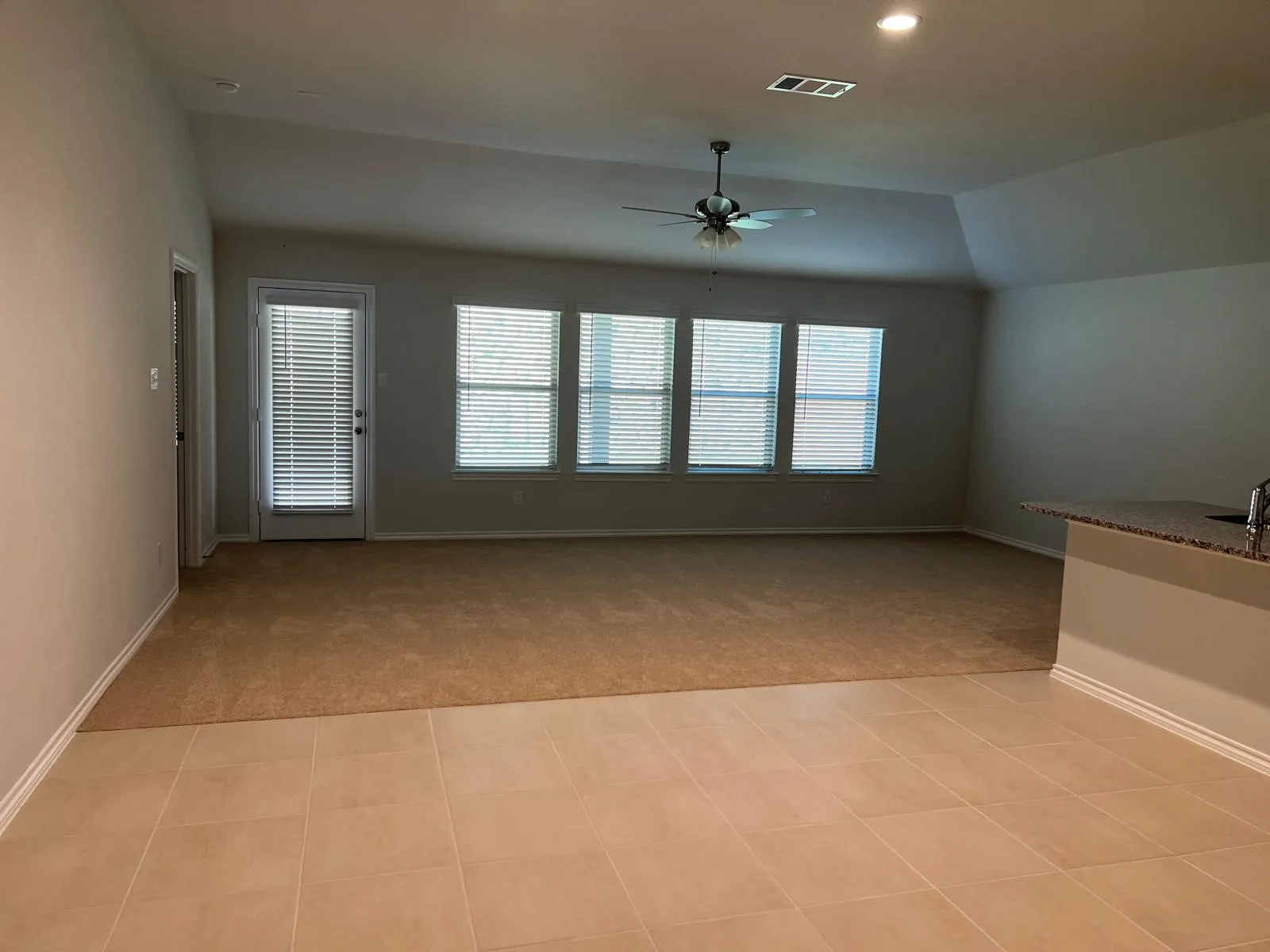 Unfurnished living room with lofted ceiling, a ceiling fan, light carpet, and recessed lighting