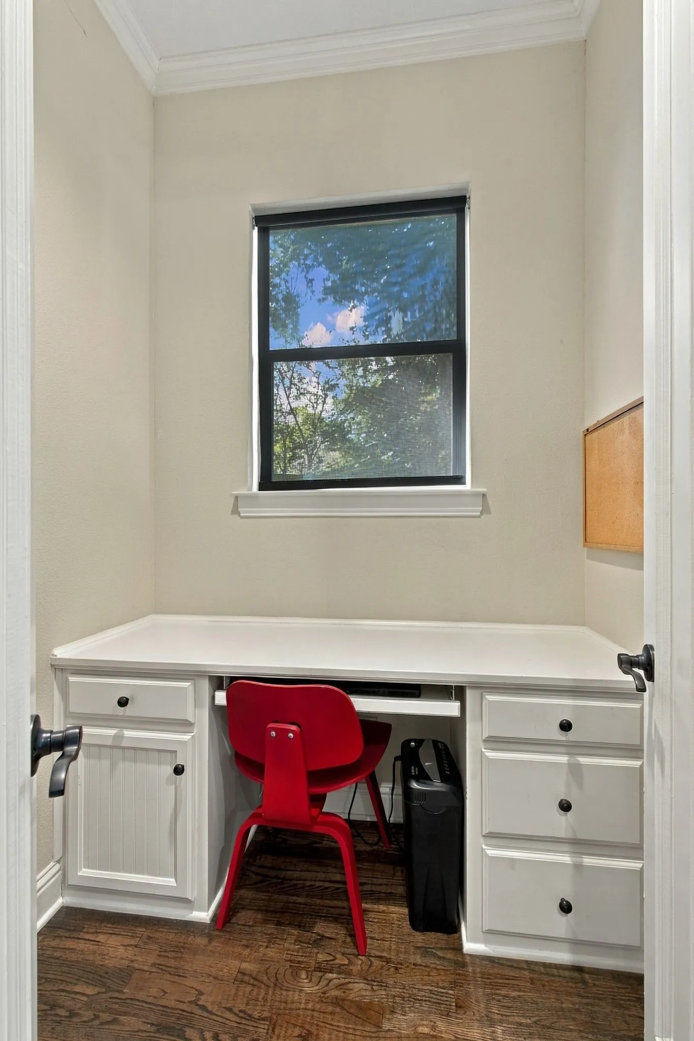 Built-in desk with cabinet storage and drawer storage, wood-finish flooring, crown molding, and a window for natural light