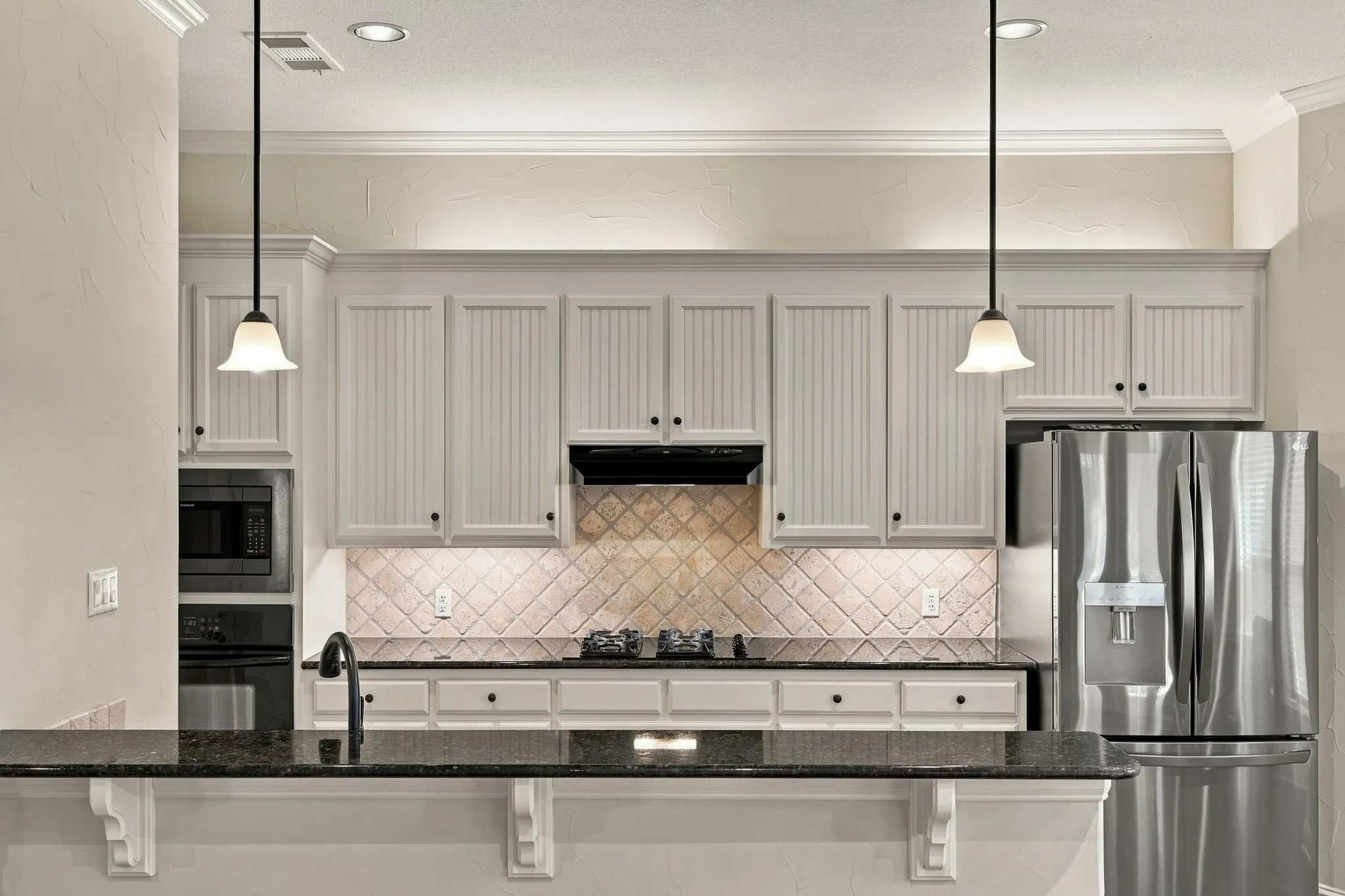 Kitchen featuring white cabinetry, a dark countertop, stainless steel appliances, a tiled backsplash, and recessed lighting