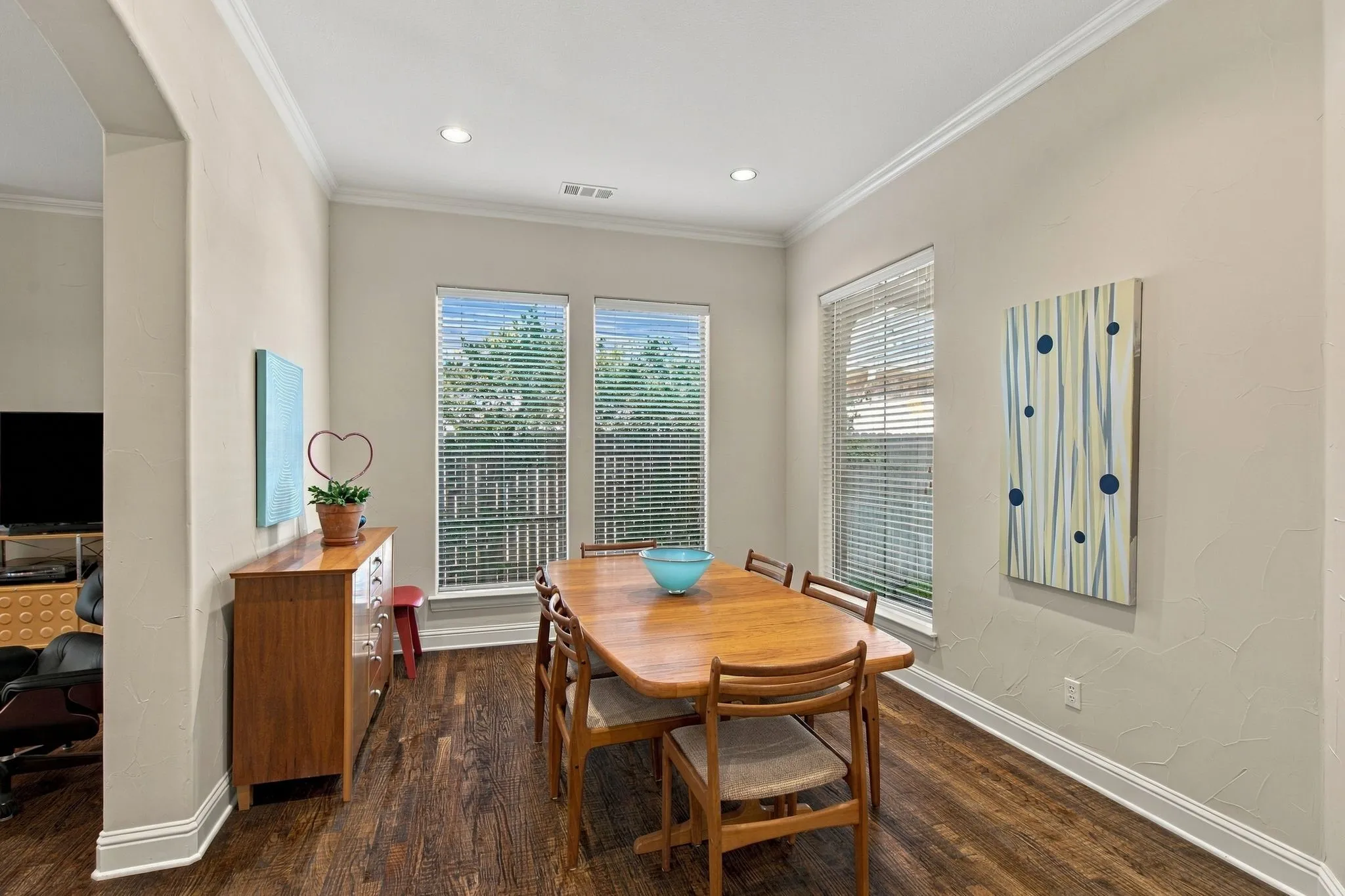 Wood-finish flooring, two large windows, recessed ceiling lighting, crown molding, and an arched entryway