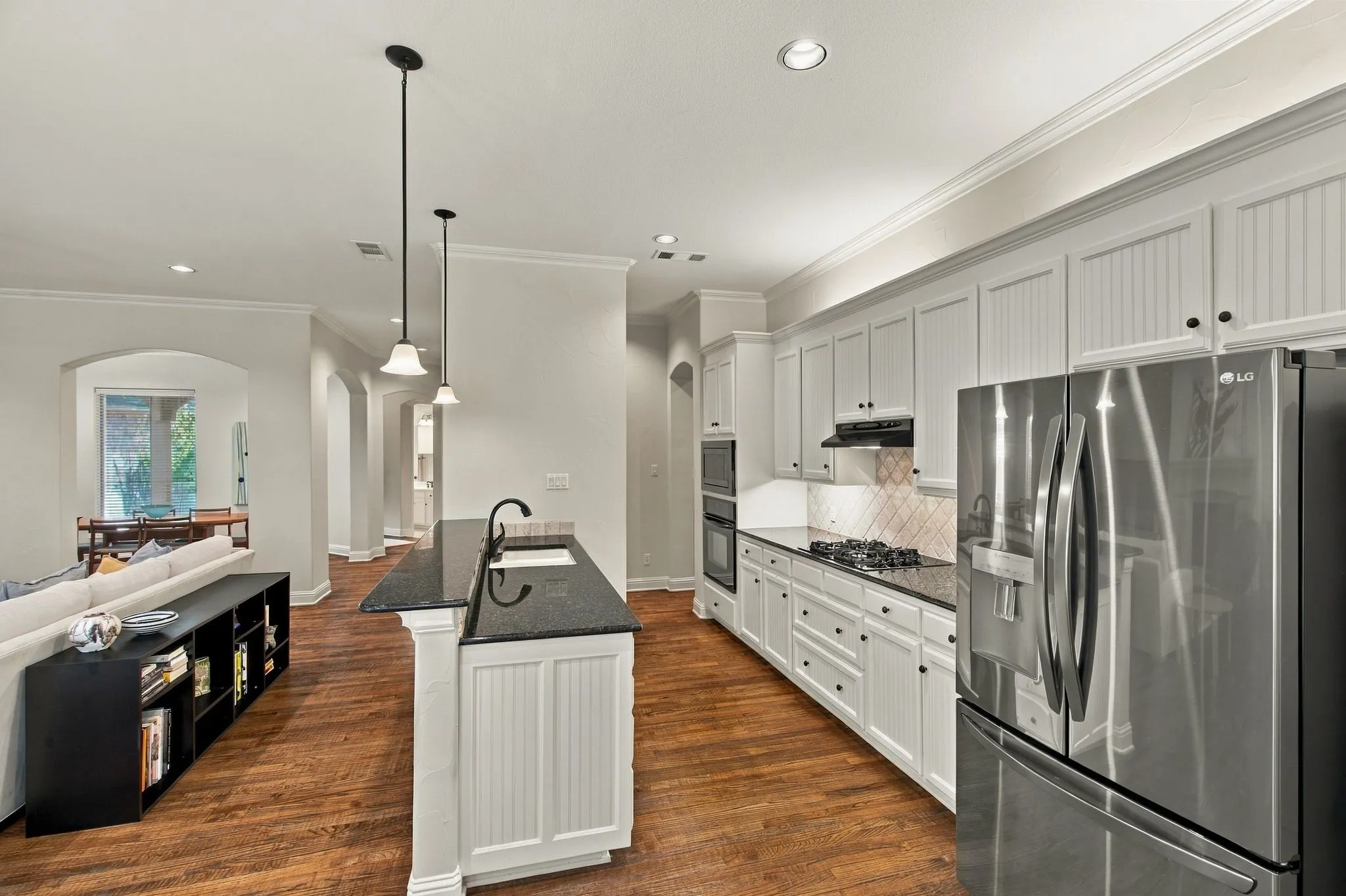 Kitchen featuring white cabinetry, dark countertops, stainless steel appliances, and wood-finish flooring