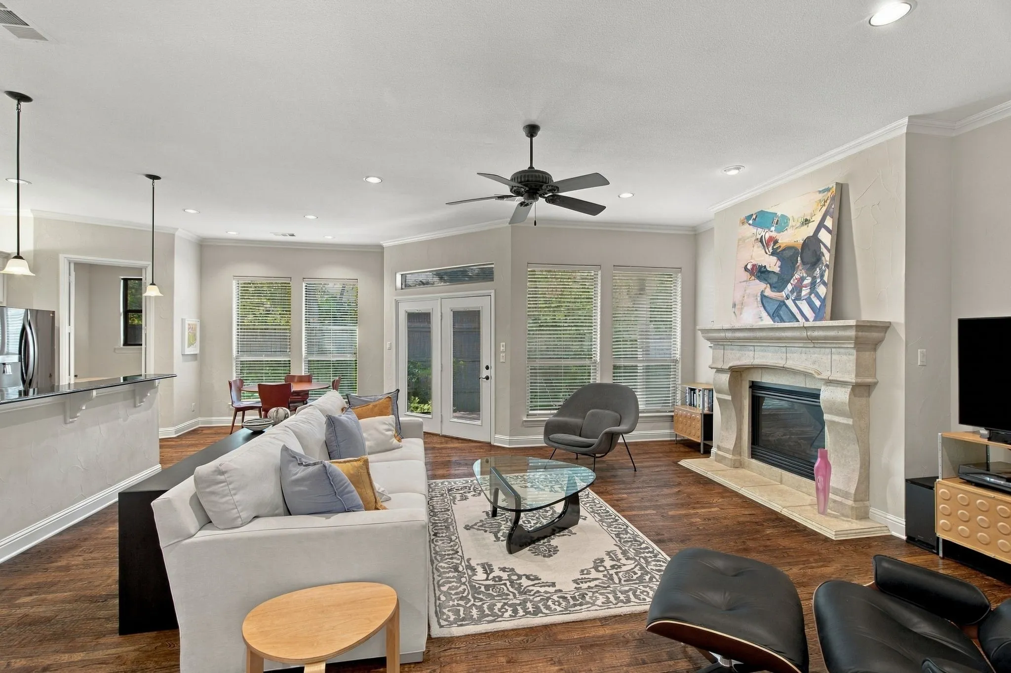 Stone-surround fireplace, wood-finish flooring, recessed lighting, ceiling fan, and crown molding