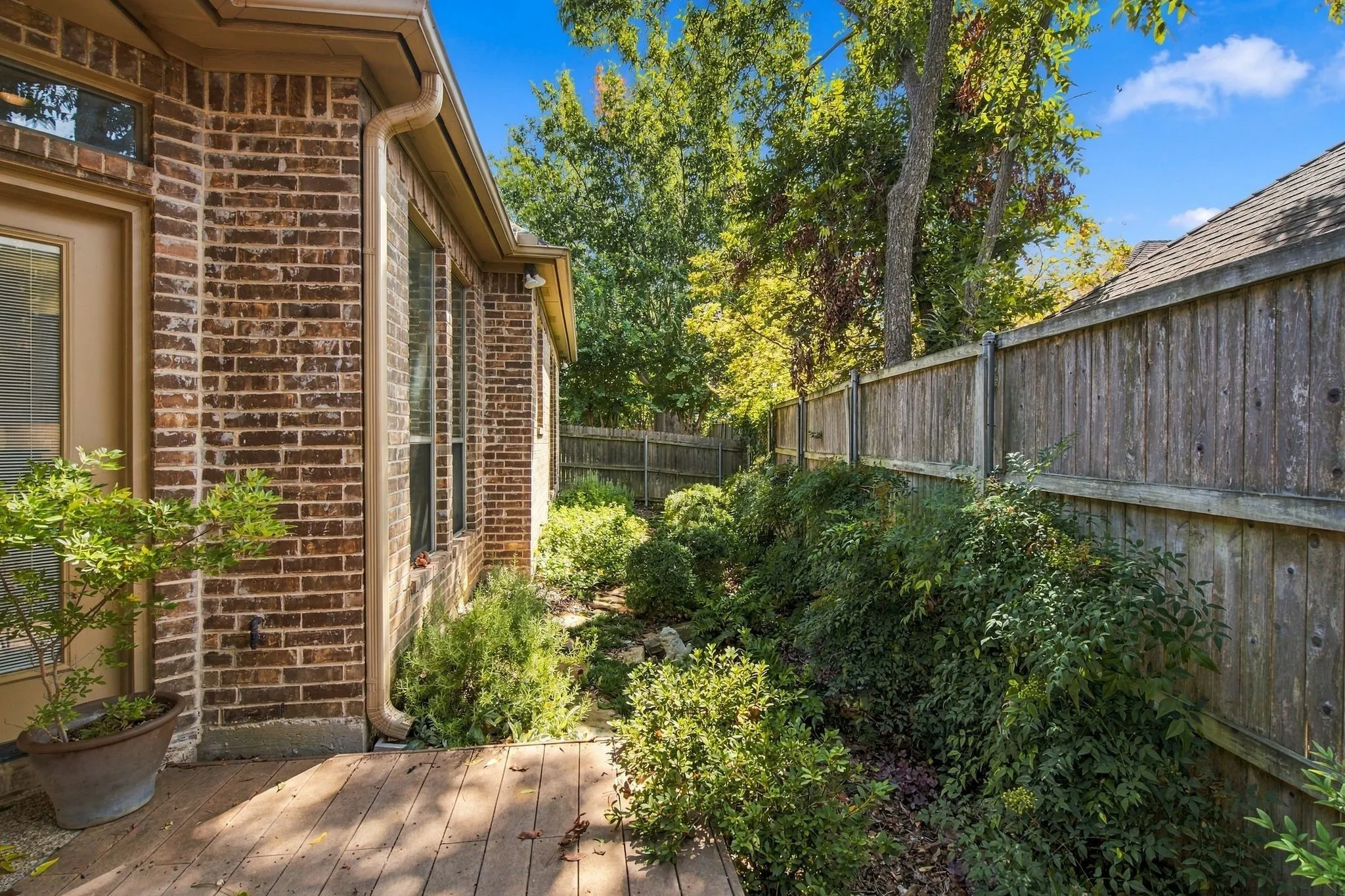 Brick exterior with multiple windows, wood deck, and a privacy fence