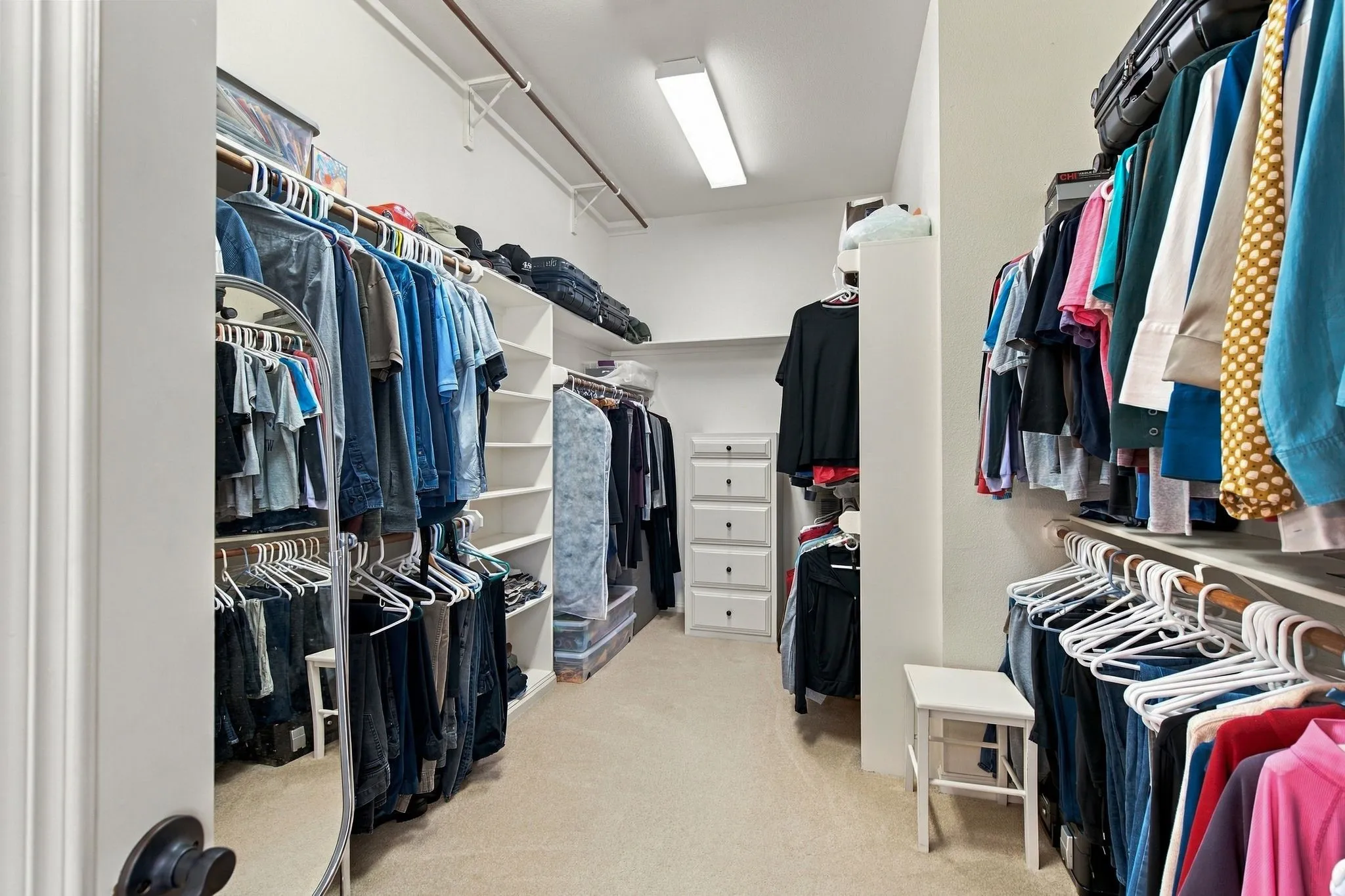 Spacious walk-in closet featuring extensive built-in shelving, multiple hanging rods, and integrated drawer storage