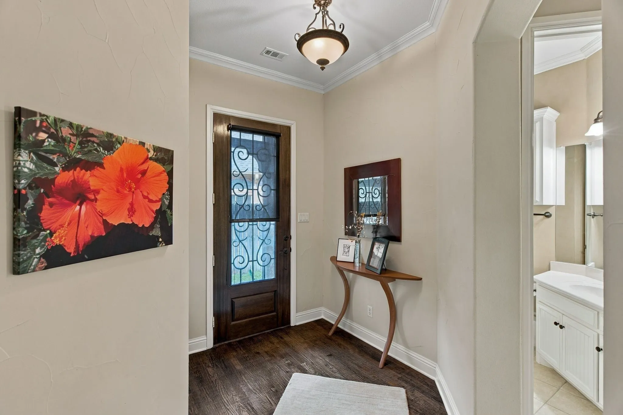 Entryway featuring wood-finish flooring, a dark wood entry door with decorative ironwork, and crown molding