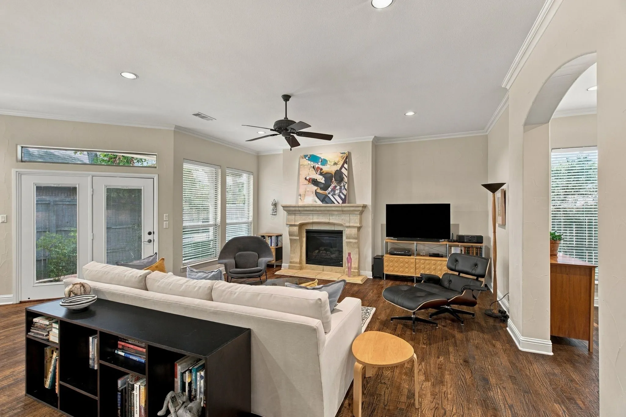 Spacious living area featuring wood-finish flooring, a stone fireplace, recessed lighting, and a ceiling fan