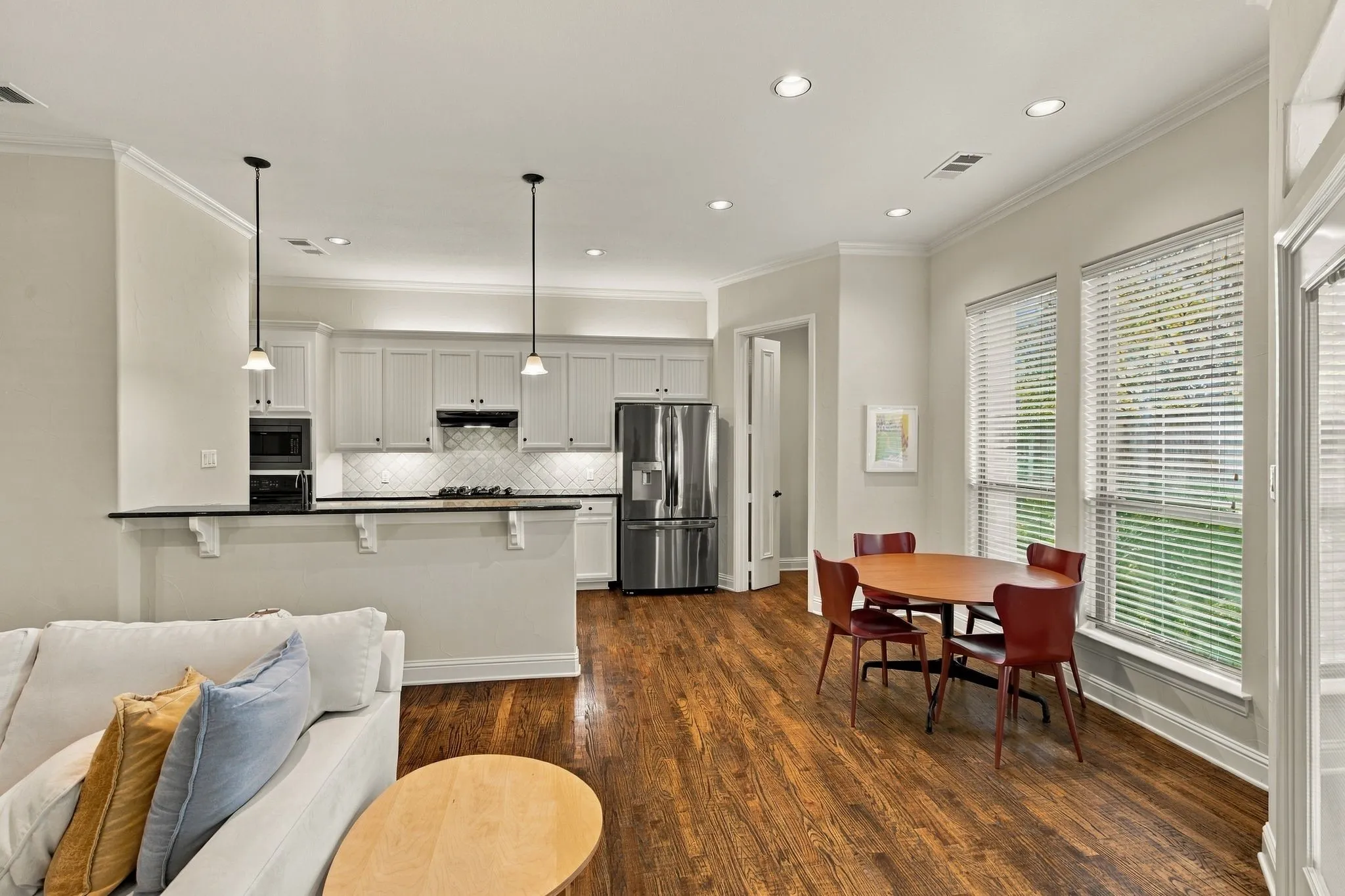 Hardwood flooring, recessed lighting, white cabinetry, stainless steel appliances, and a tiled kitchen backsplash