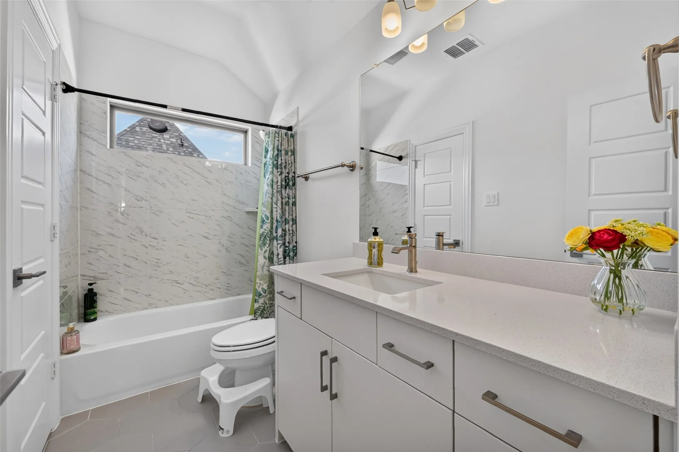 Modern bathroom featuring a single vanity with stone countertop, undermount sink, and brushed nickel faucet