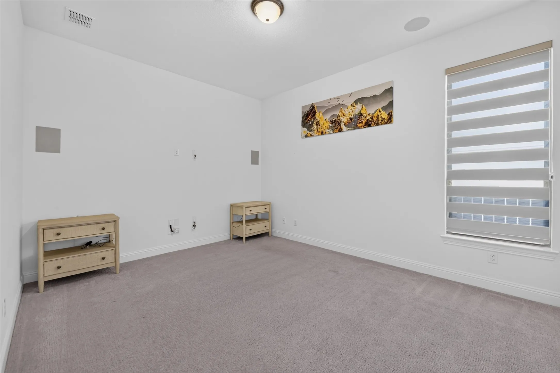 Recessed ceiling speaker, wall-mounted speakers, ceiling light fixture, window with layered blinds, and carpeted flooring