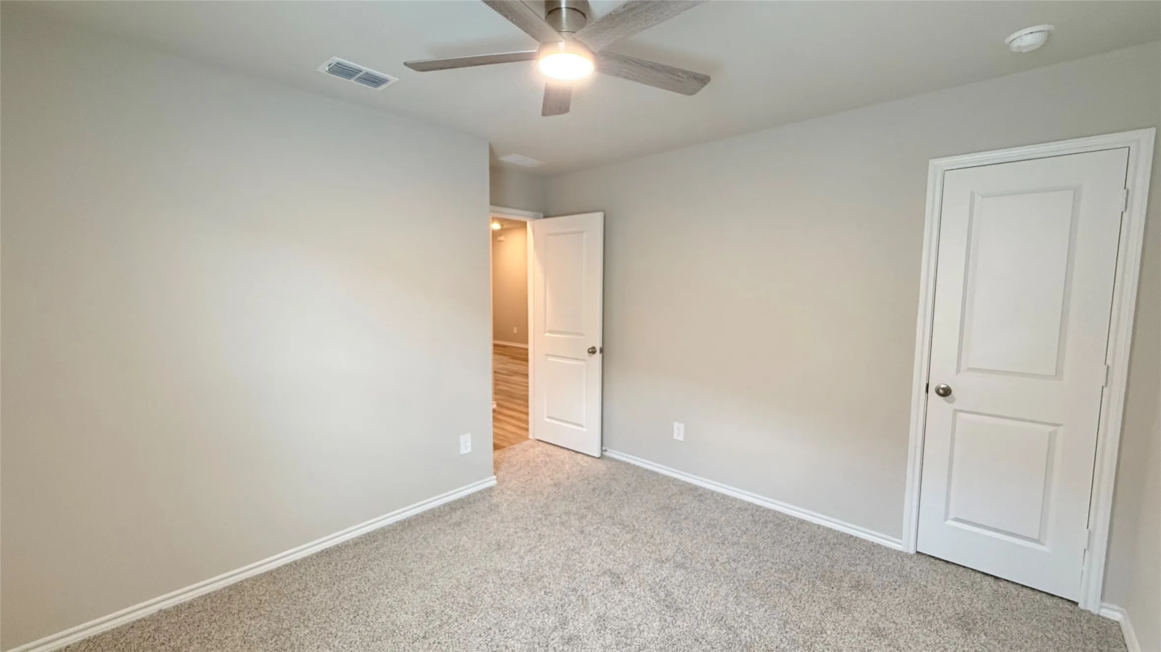 Neutral wall paint, carpet flooring, ceiling fan with integrated lighting, and white paneled doors