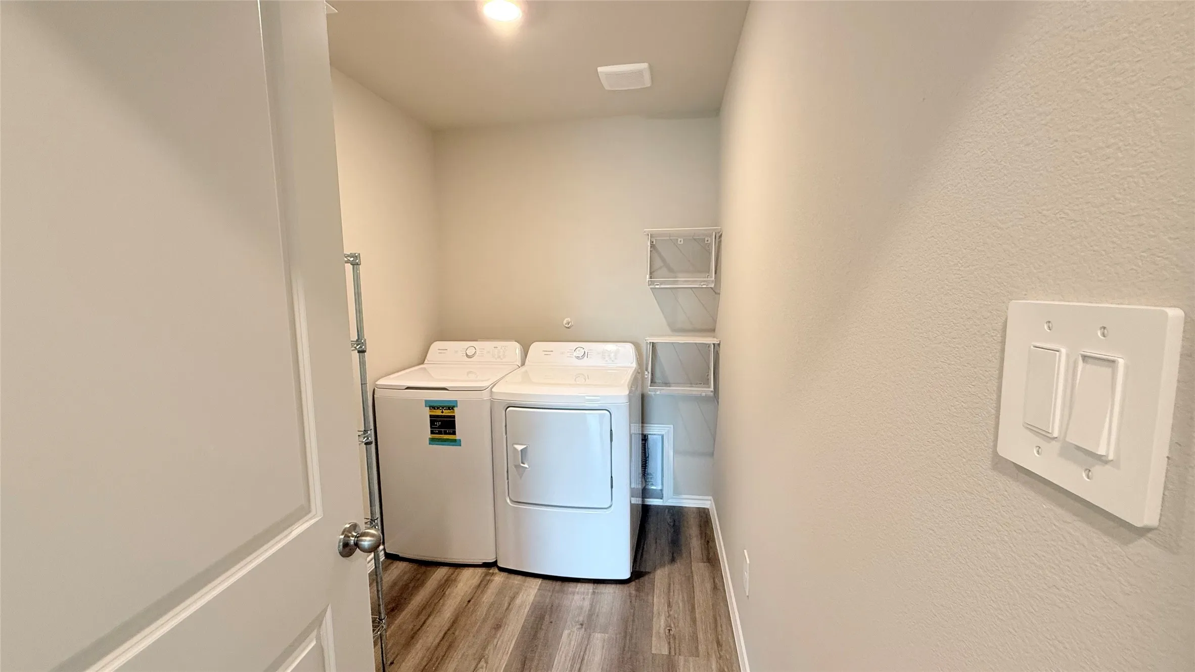 Dedicated laundry area with a washer, dryer, wood-finish flooring, and built-in wire shelving