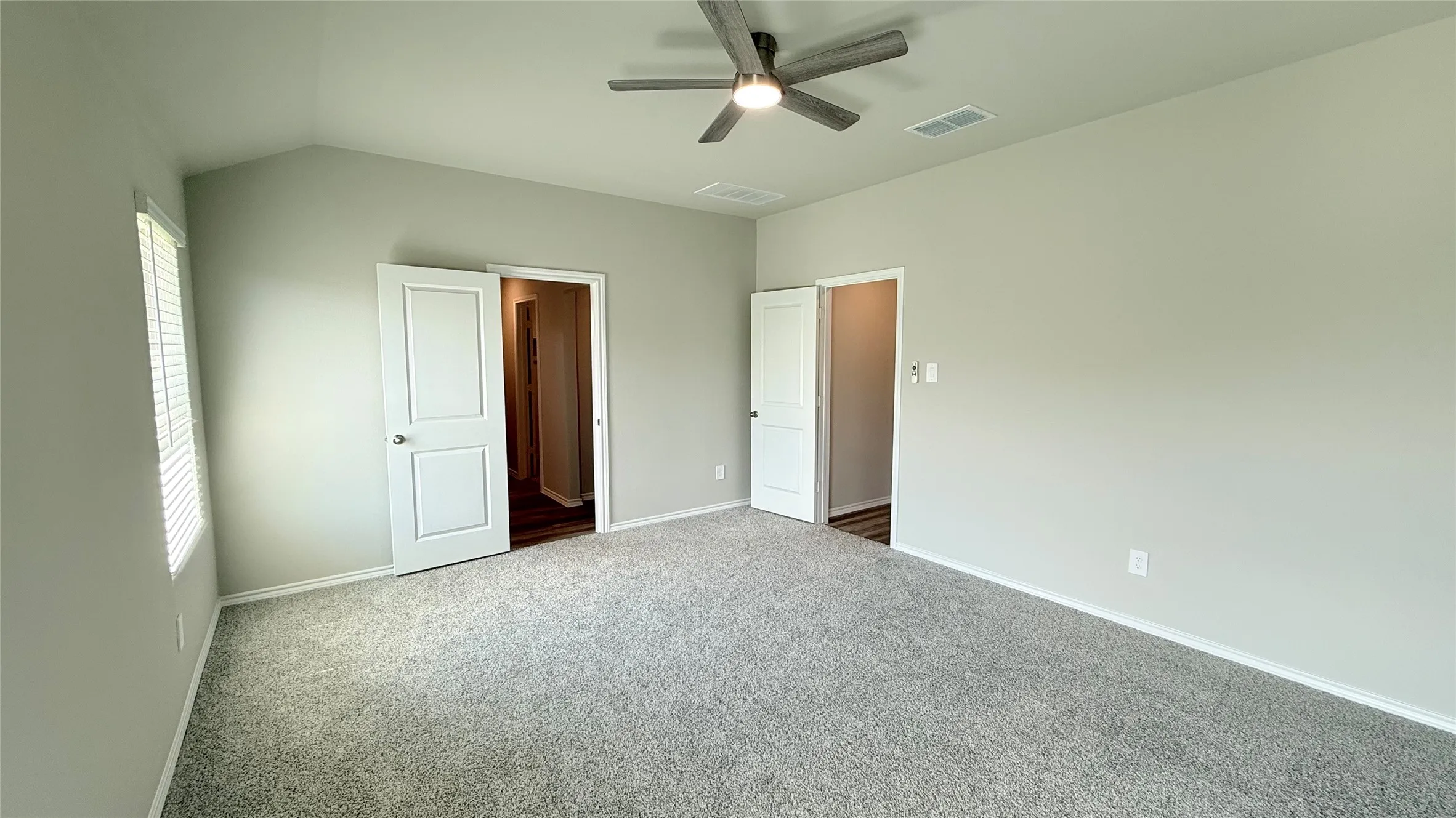 Vaulted ceiling, ceiling fan, neutral paint, carpet flooring, and white trim