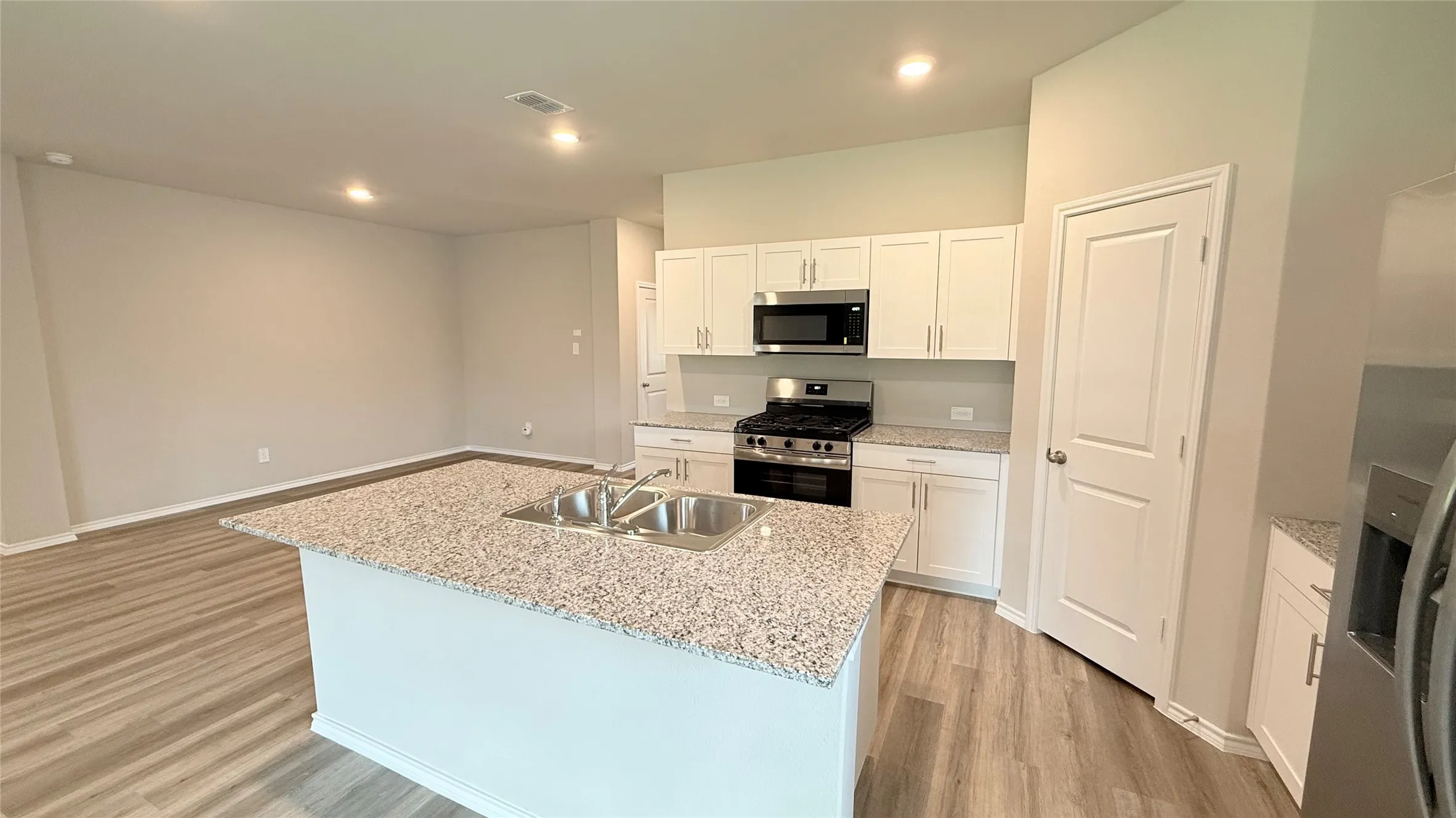 Kitchen island with a double basin stainless steel sink and light granite-style countertop