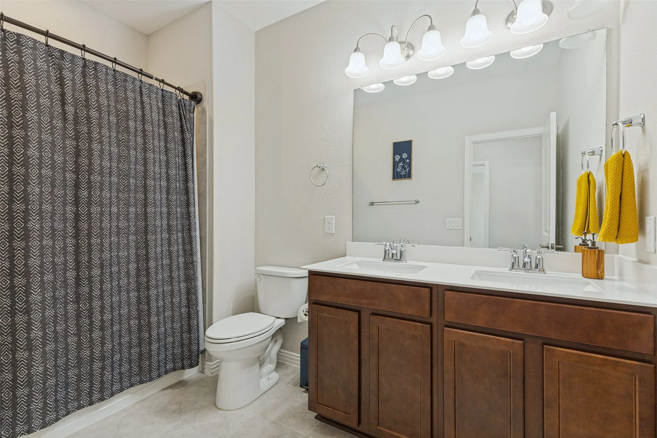 Dual vanity with white countertops, wood-finish cabinetry, and chrome fixtures