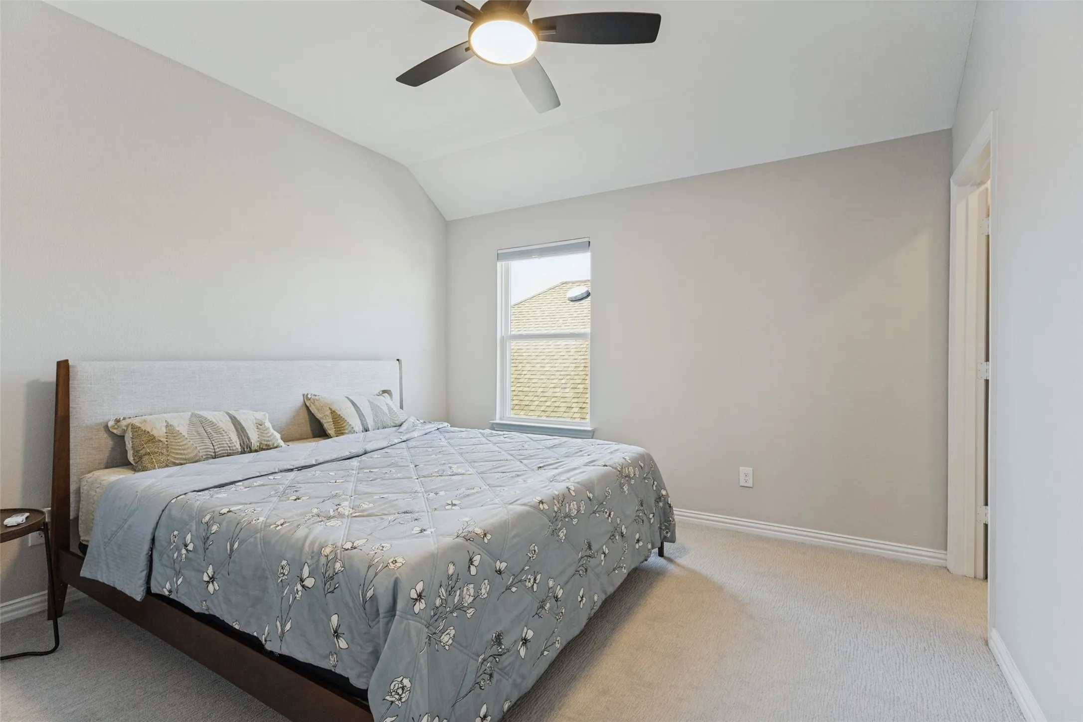 Vaulted ceiling bedroom featuring carpeting, a ceiling fan, and a window