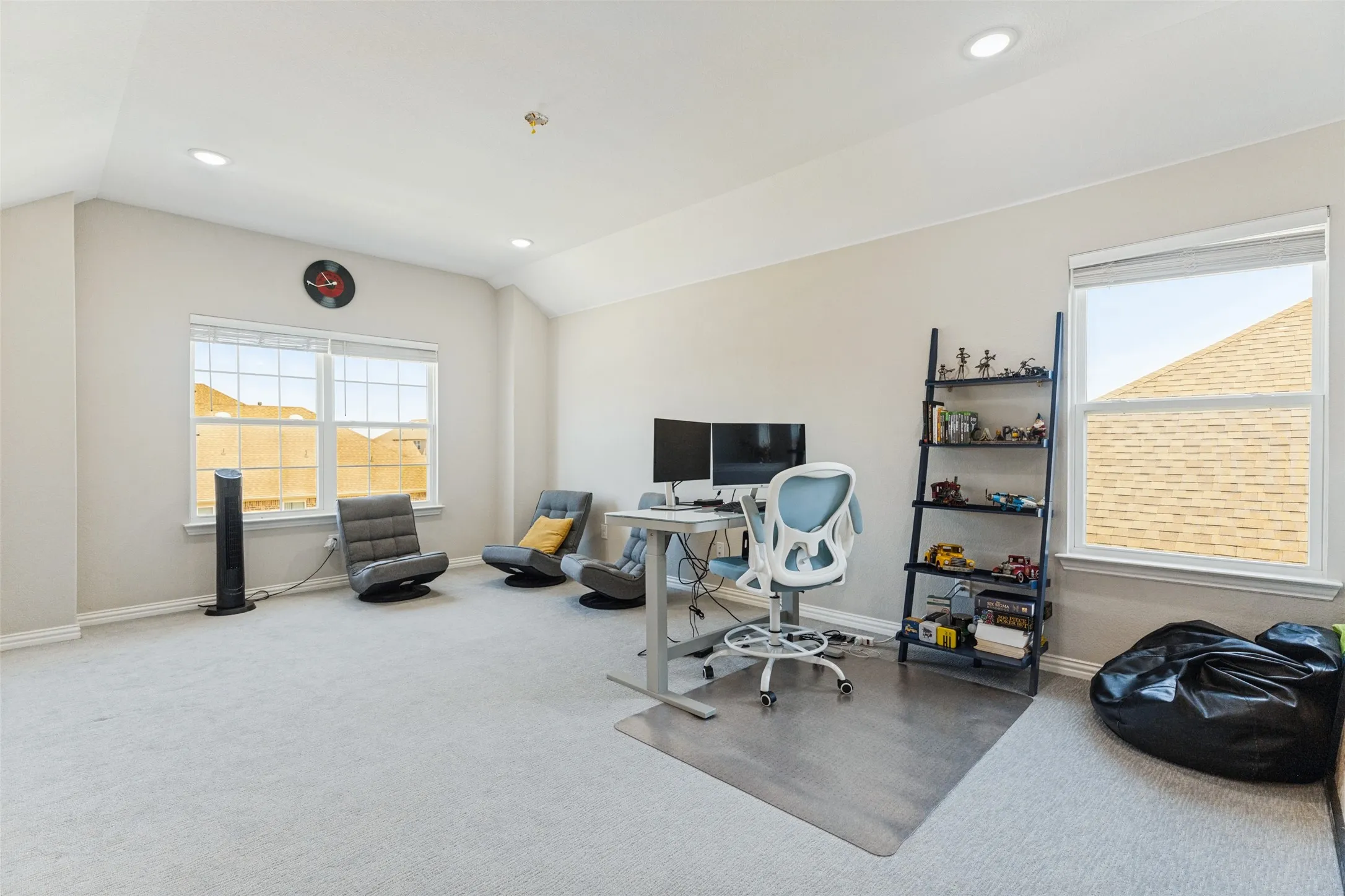 Carpeted room featuring vaulted ceilings, recessed lighting, and multiple windows