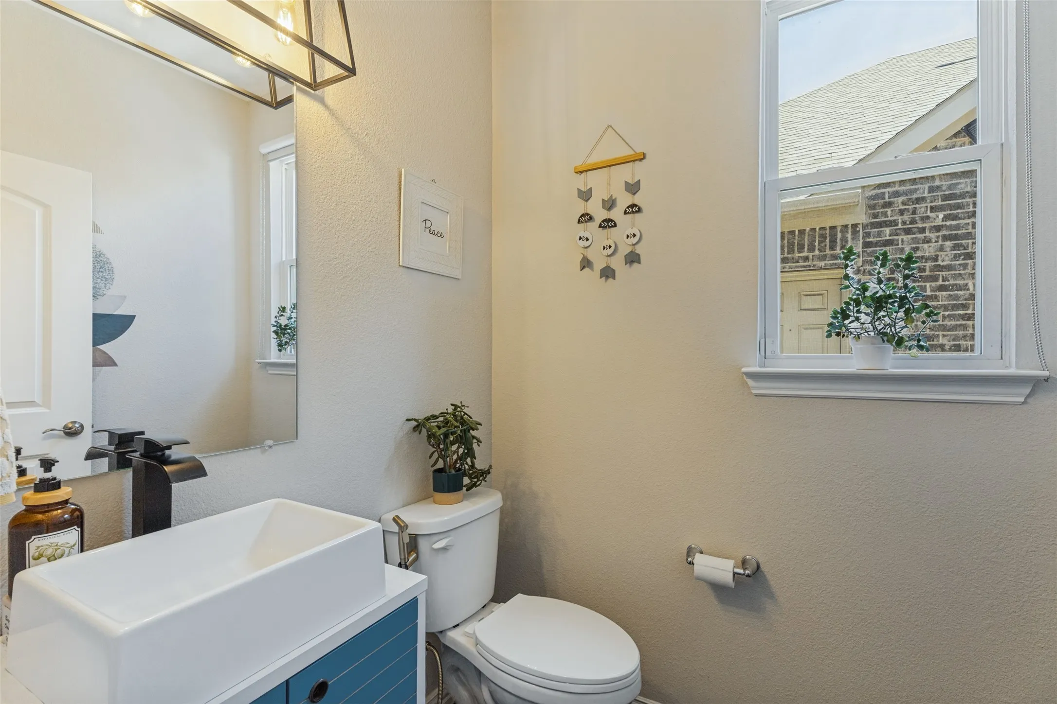 Recessed window with white trim, contemporary vanity with a vessel sink, and matte black faucet