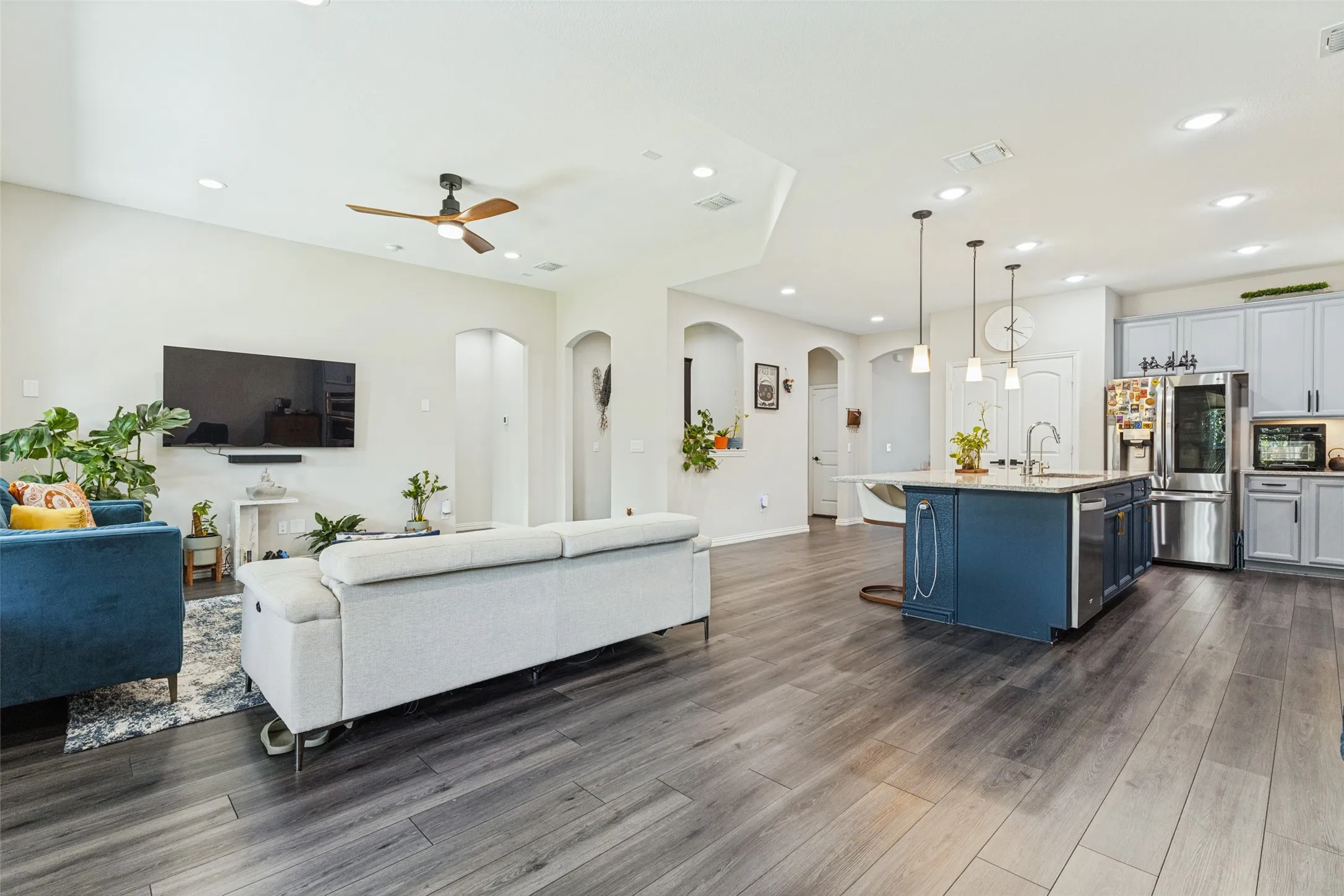 Spacious open-concept living area featuring wood-finish flooring, recessed lighting, and a ceiling fan