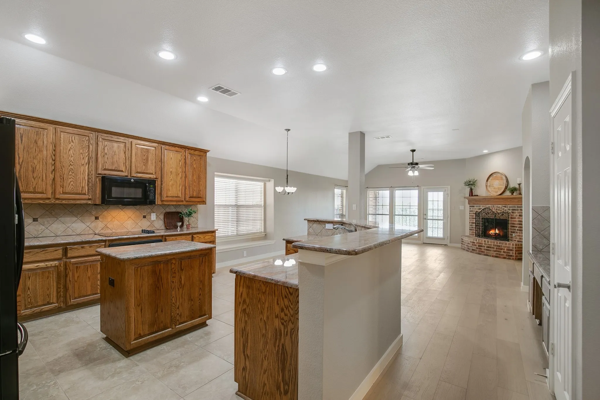 Spacious kitchen with wood cabinetry, stone countertops, and a central island