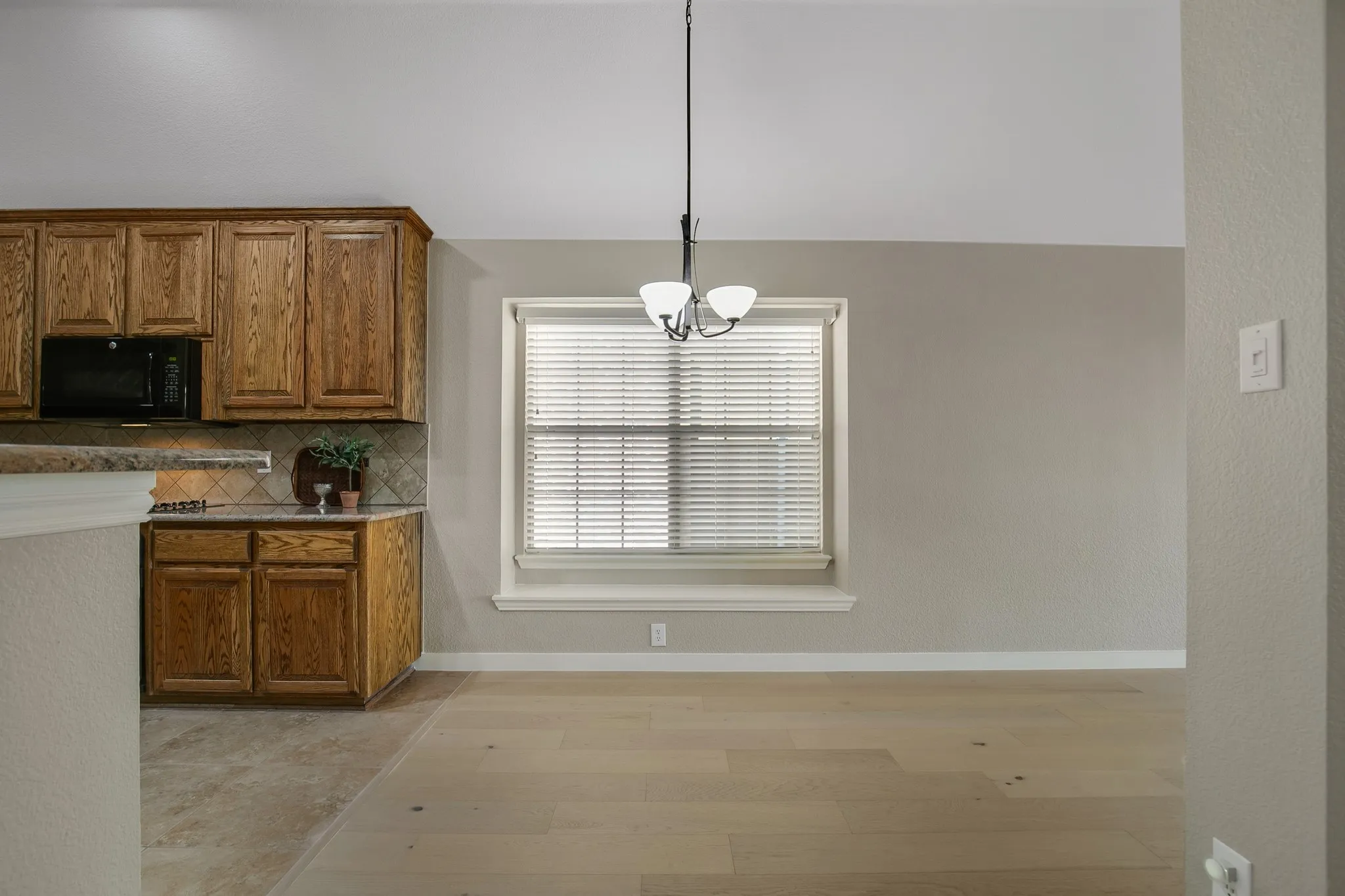 Kitchen featuring wood cabinetry, built-in microwave, tile backsplash, and light-toned countertop