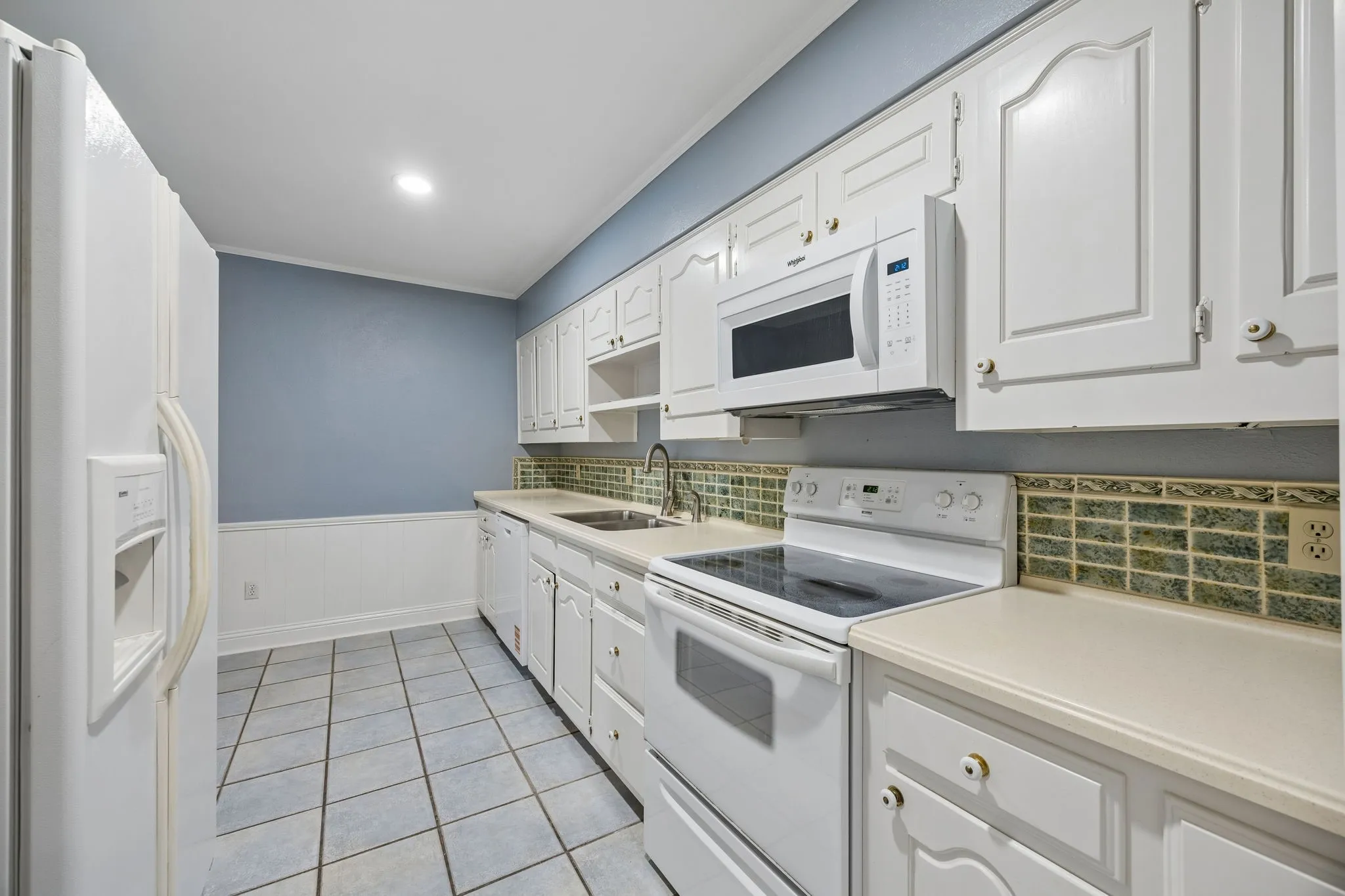 Bright kitchen with white cabinetry, ample counter space, and a tiled backsplash.