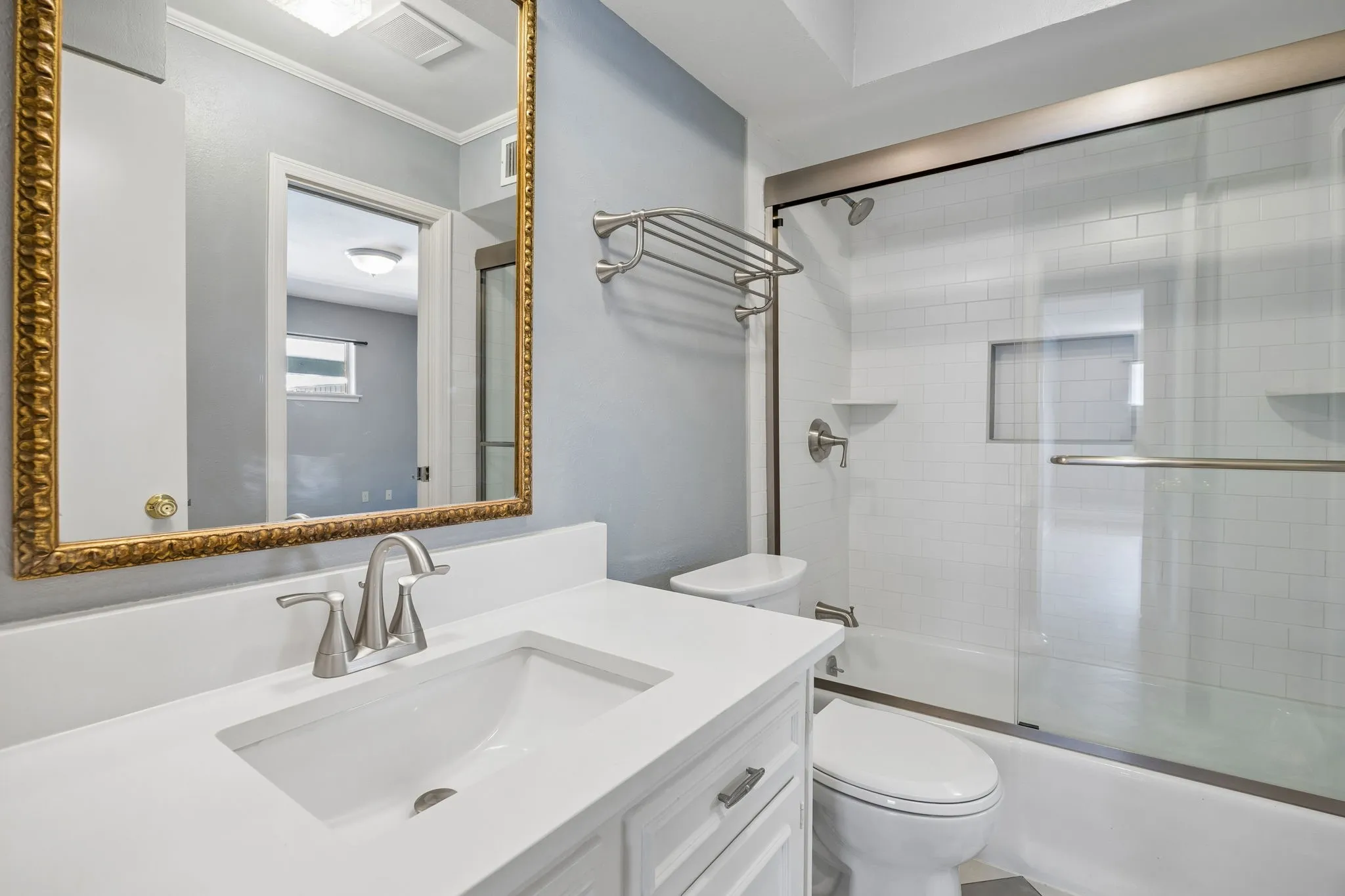 Secondary bath with a white vanity, quartz countertop, and tub-shower combination with subway tile surround.