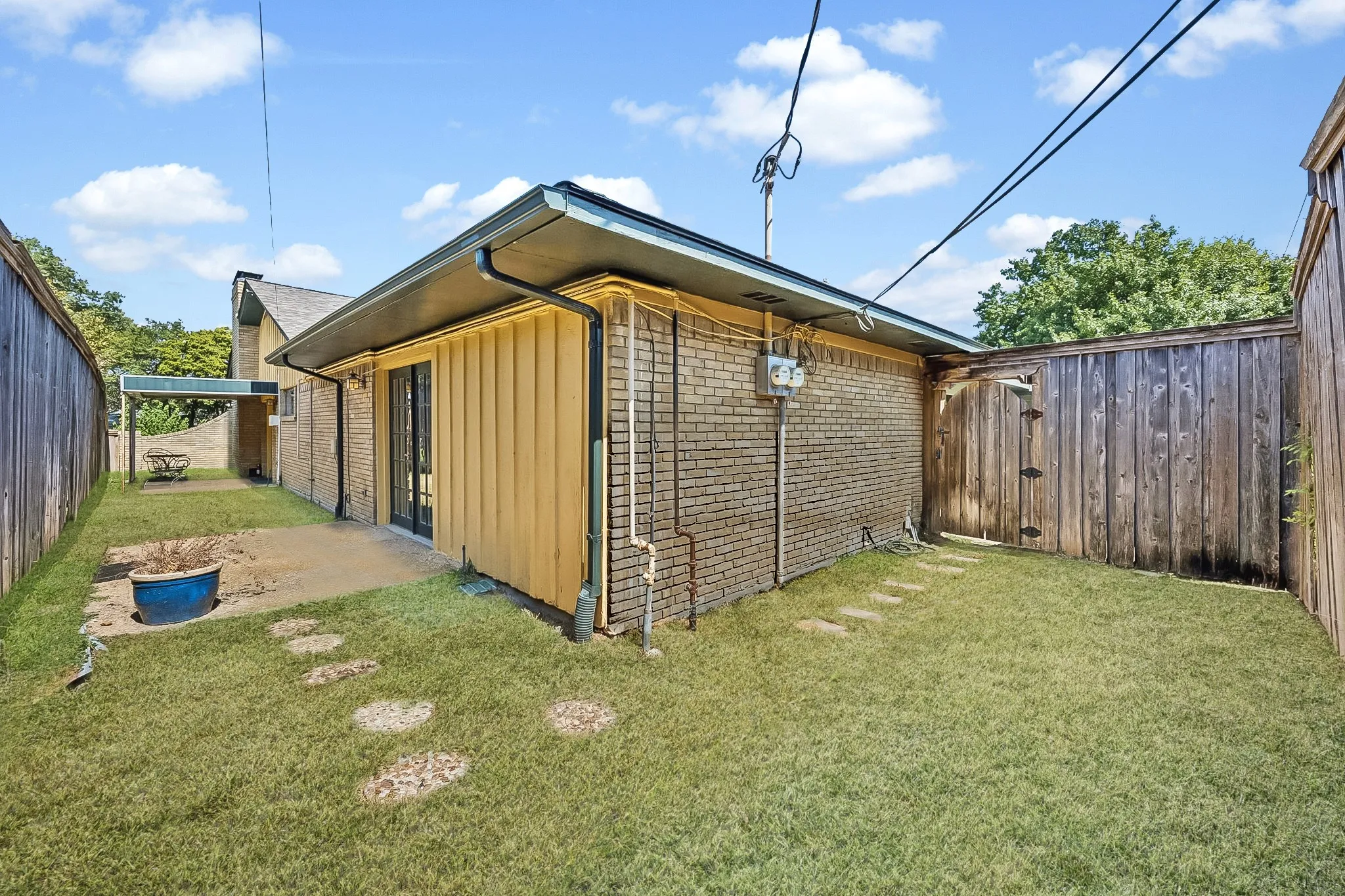 Fenced backyard with a grassy side yard for added functionality.