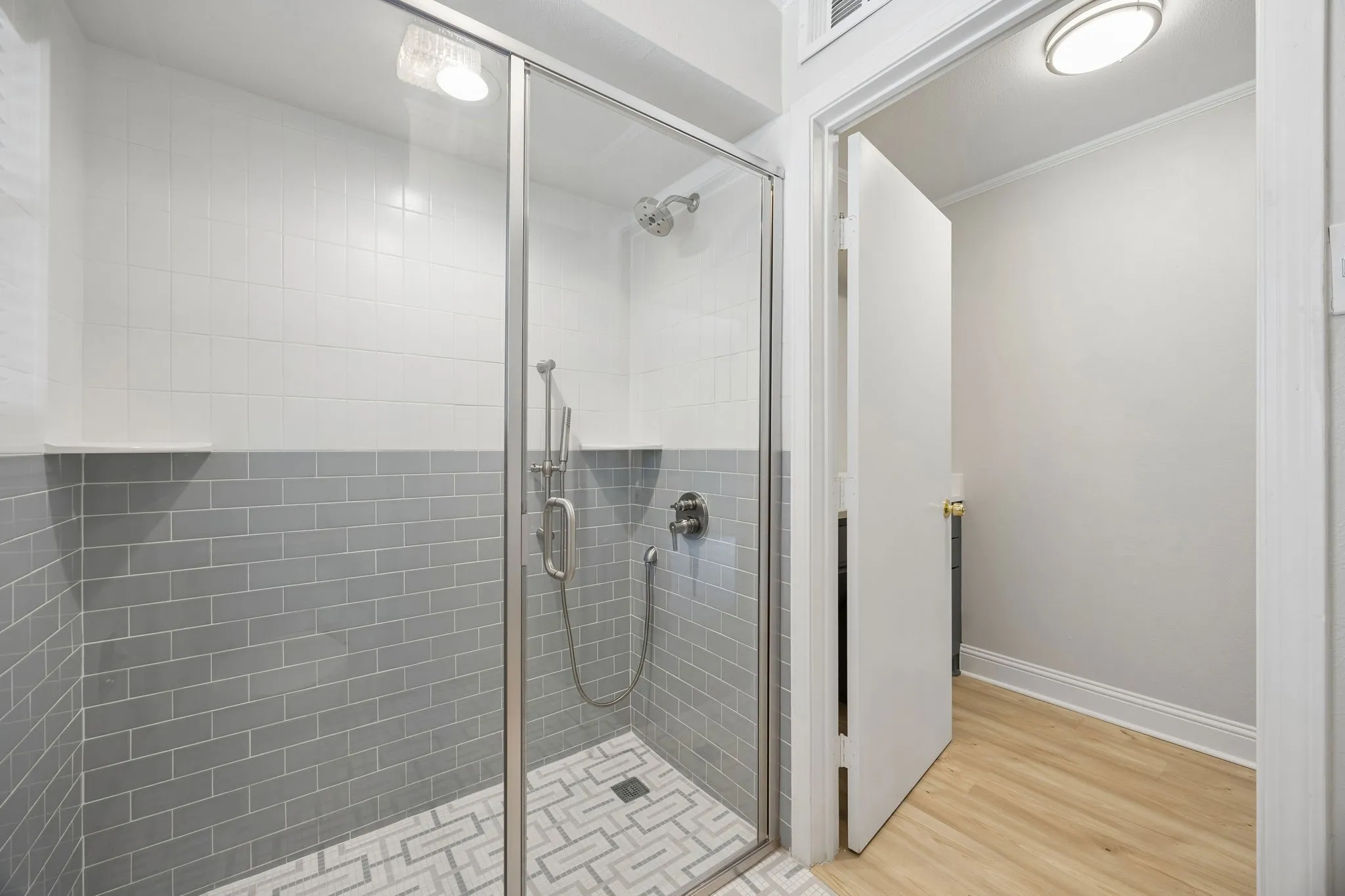 Primary bath with a glass-enclosed shower featuring dual shower heads and a clean, modern finish.