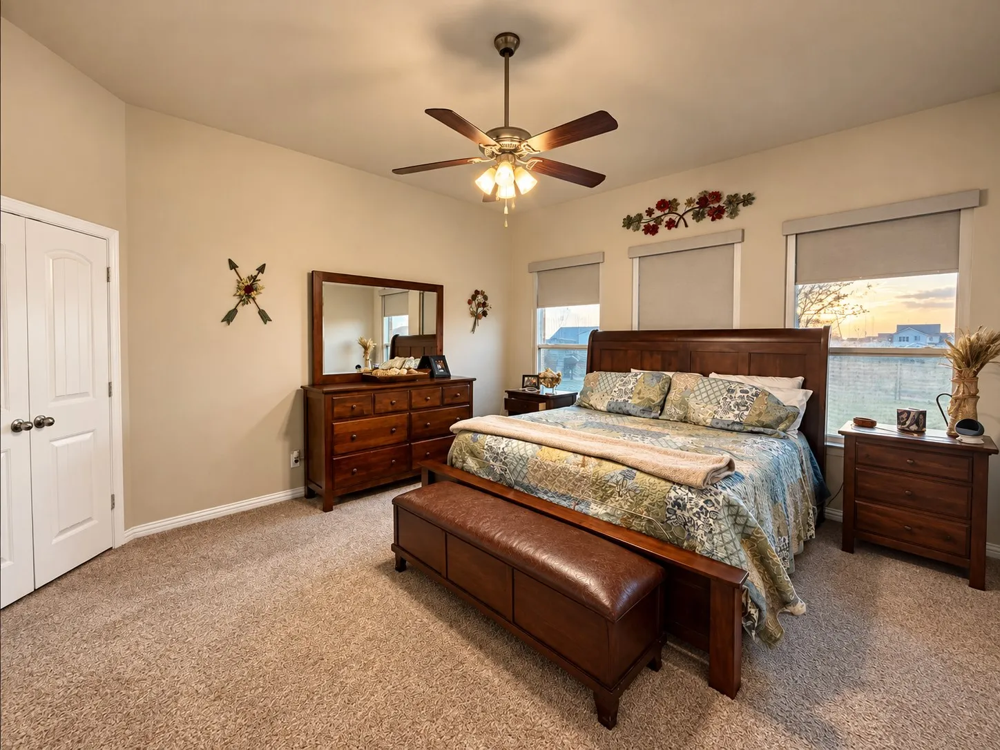 Vaulted ceiling, ceiling fan with integrated lighting, textured carpeting, double-door closet, and three windows with roller shades