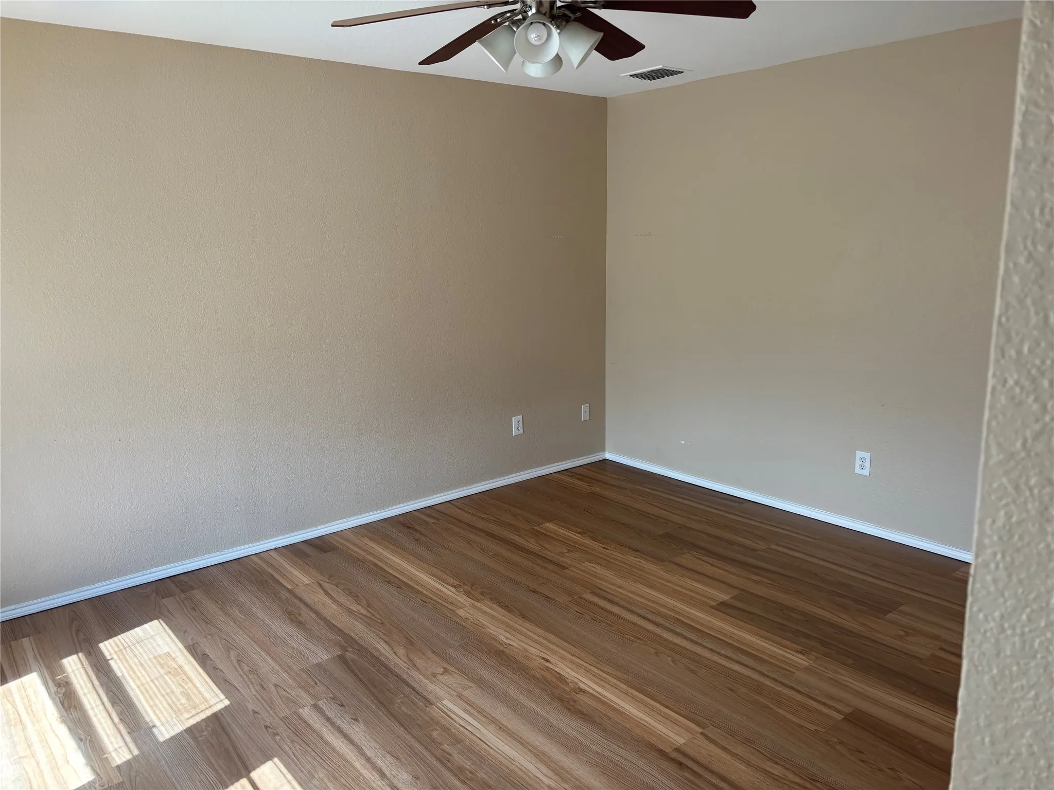 Wood-finish flooring with neutral wall tones and a ceiling-mounted fan
