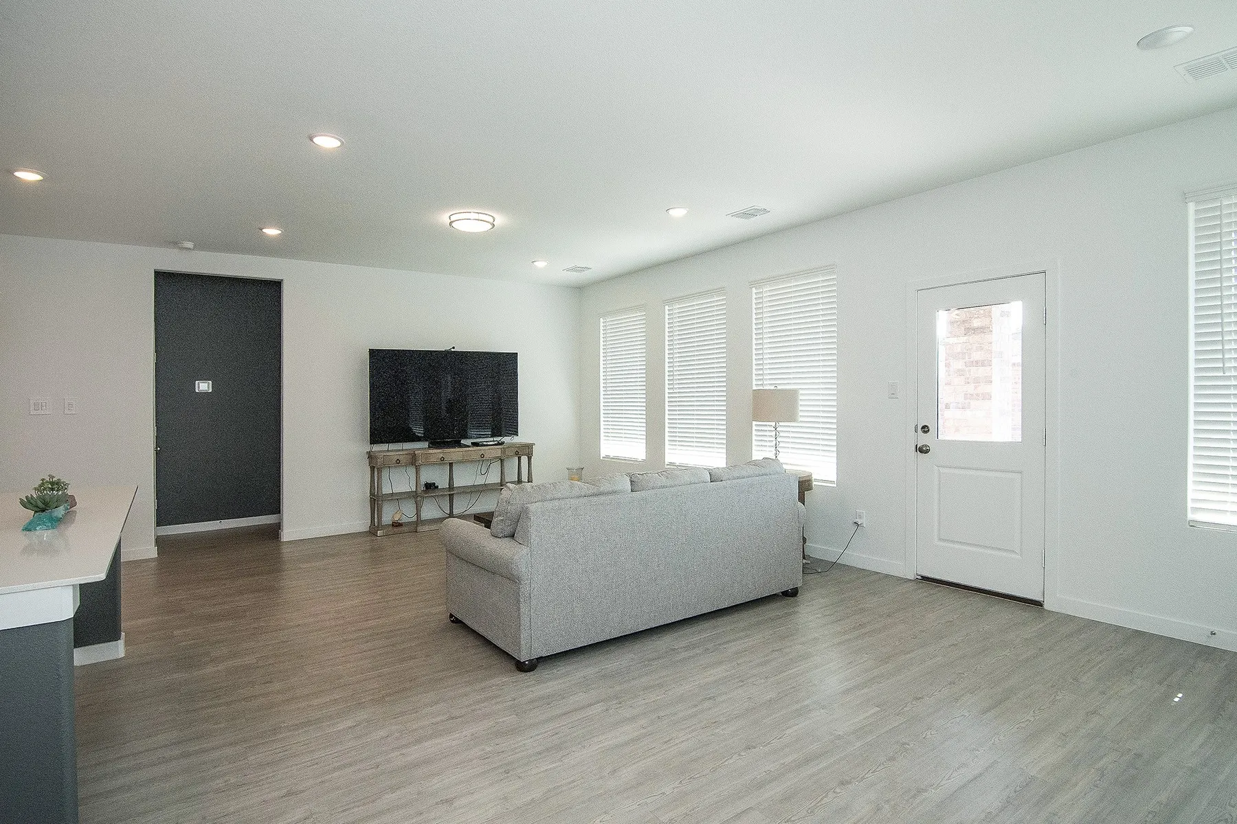 Wood-finish flooring throughout, recessed lighting, and multiple windows with blinds