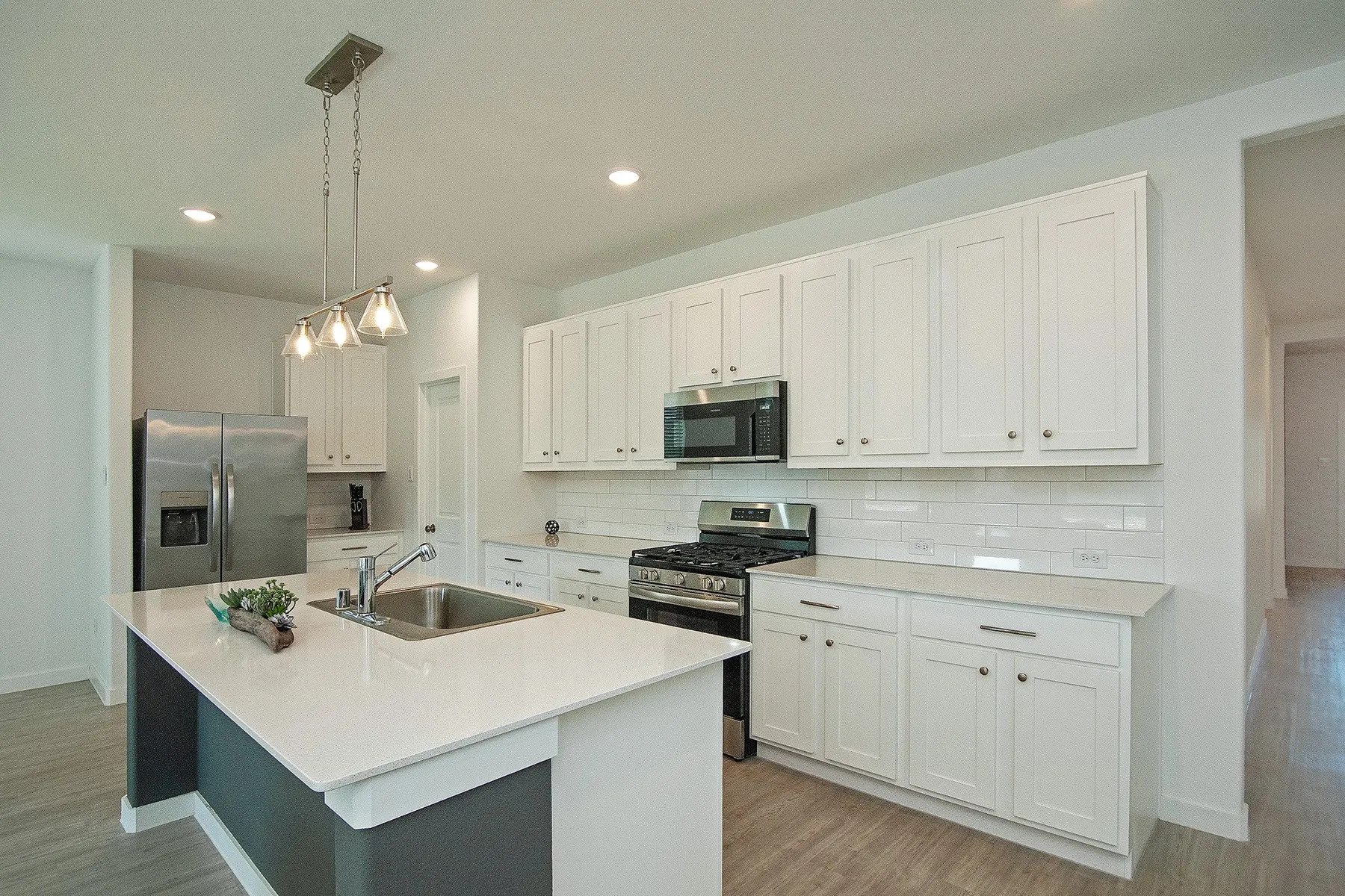 Kitchen featuring white shaker cabinetry, stainless steel appliances, a subway tile backsplash, and light-toned countertops