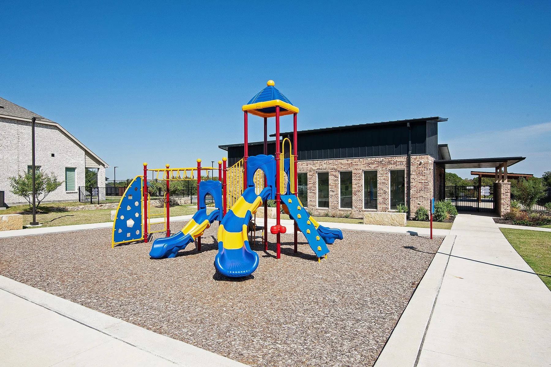 Contemporary play structure with multiple slides and climbing elements, set on a cushioned ground surface