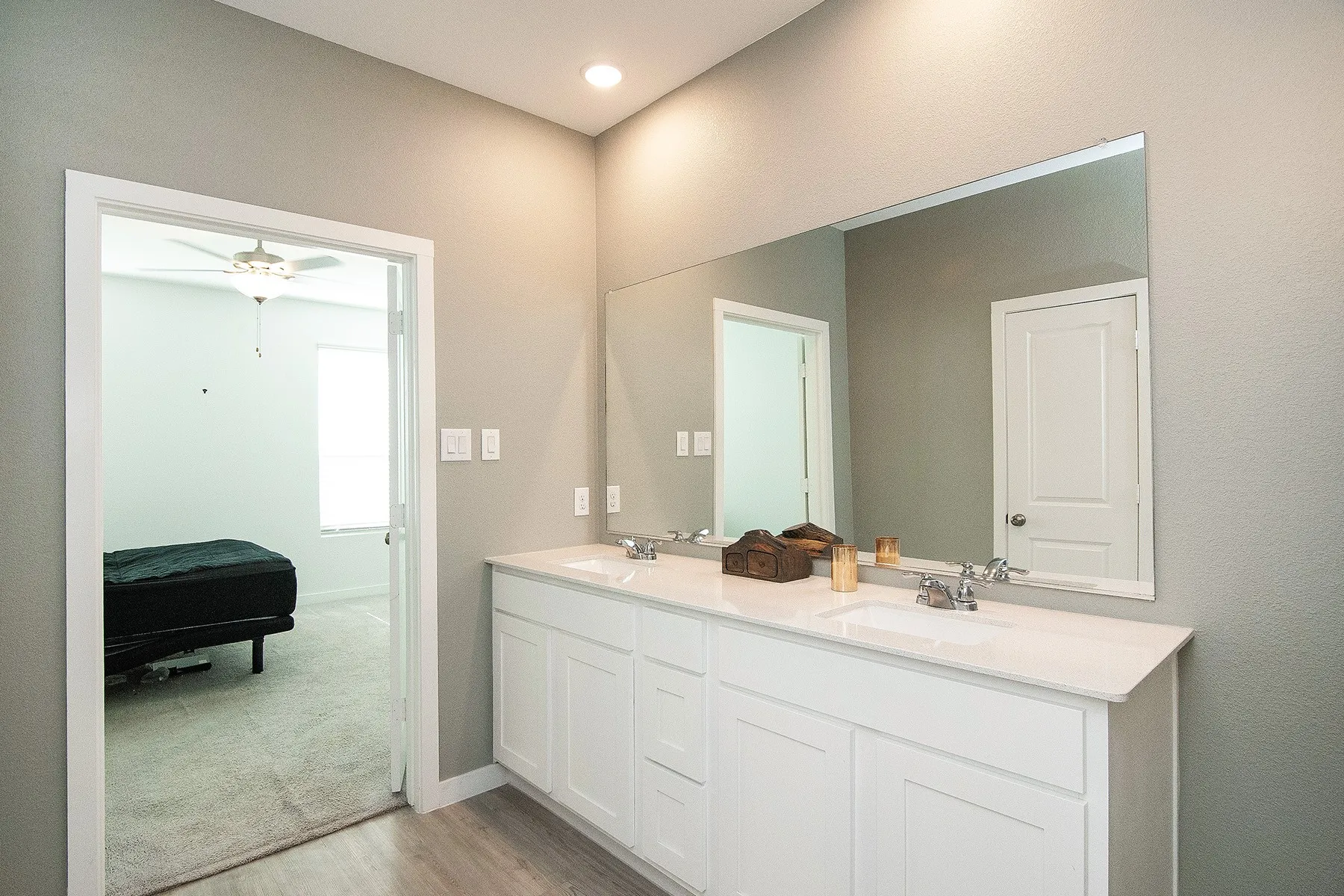 Double vanity with white cabinetry, integrated sinks, chrome fixtures, and a spacious wall-mounted mirror