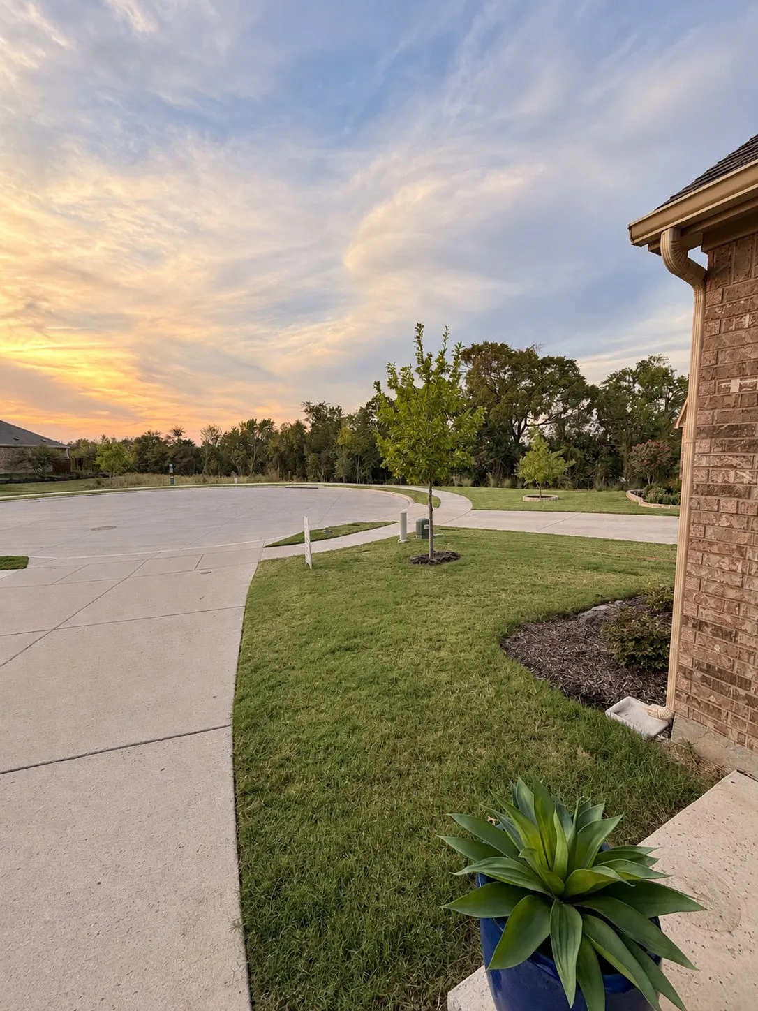 Brick exterior with tan gutters, concrete pathways, and a landscaped lawn