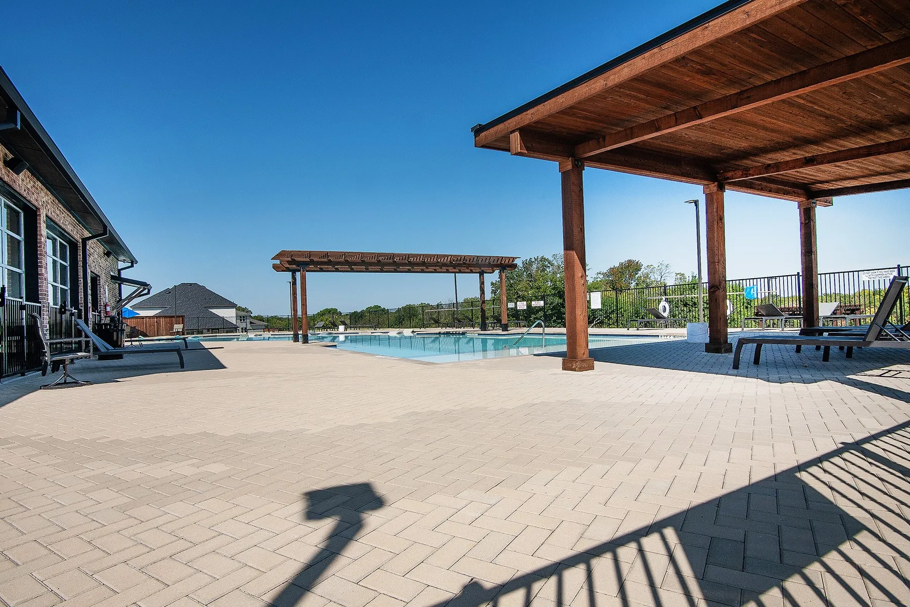 Spacious paver patio with multiple pergolas and a full-size swimming pool