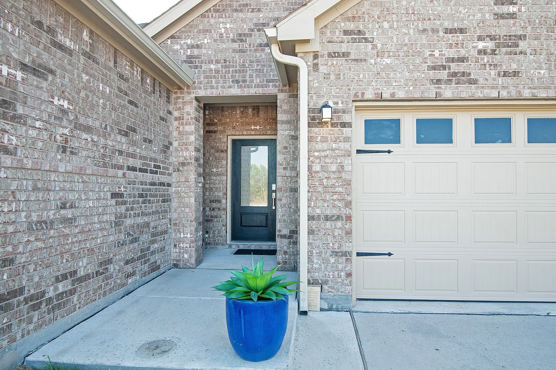 Brick exterior with a recessed entryway, a dark-paneled door with glass inserts, and an attached garage with decorative hardware