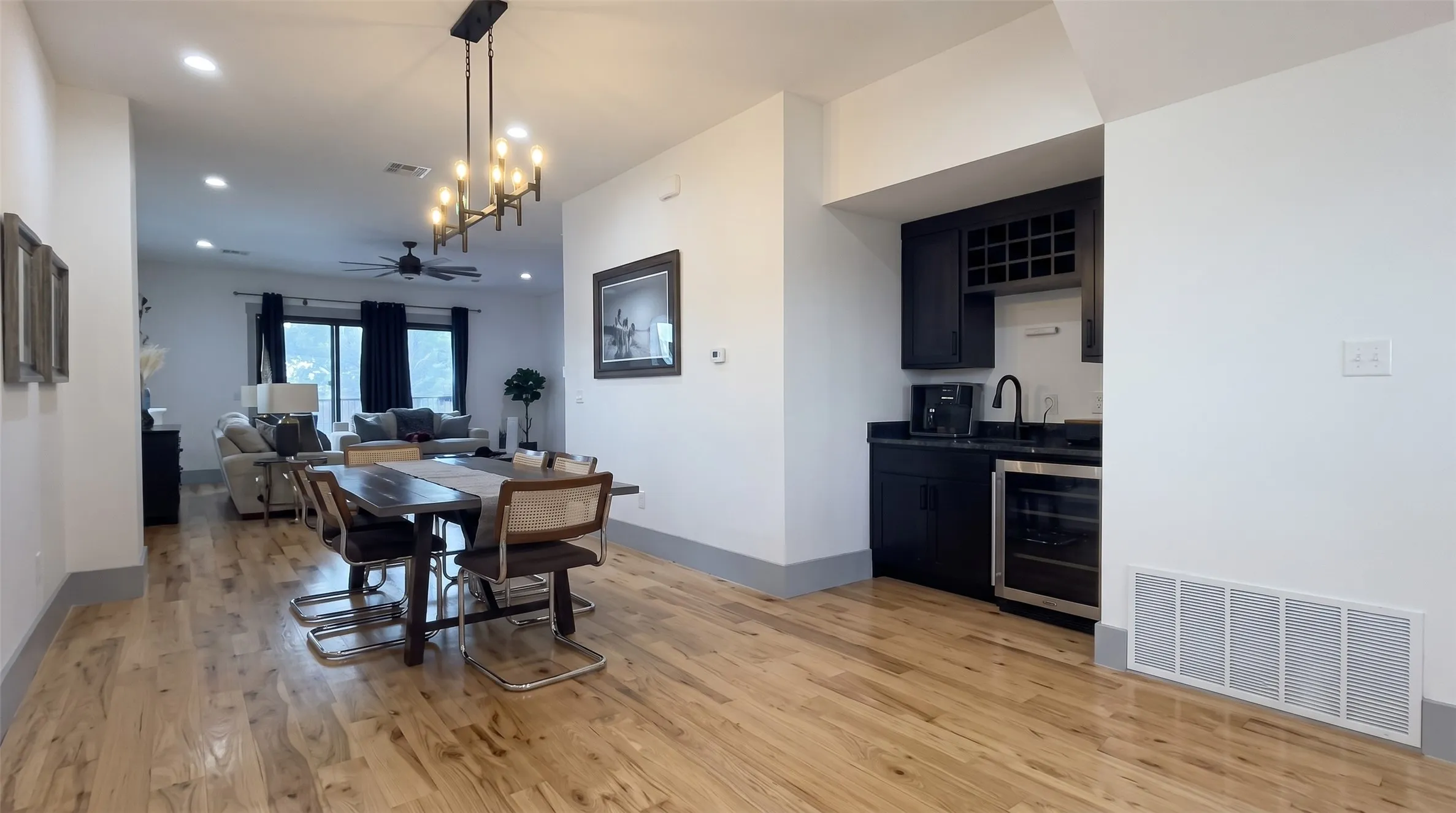 Hardwood flooring throughout, recessed lighting, and a linear chandelier in the dining area